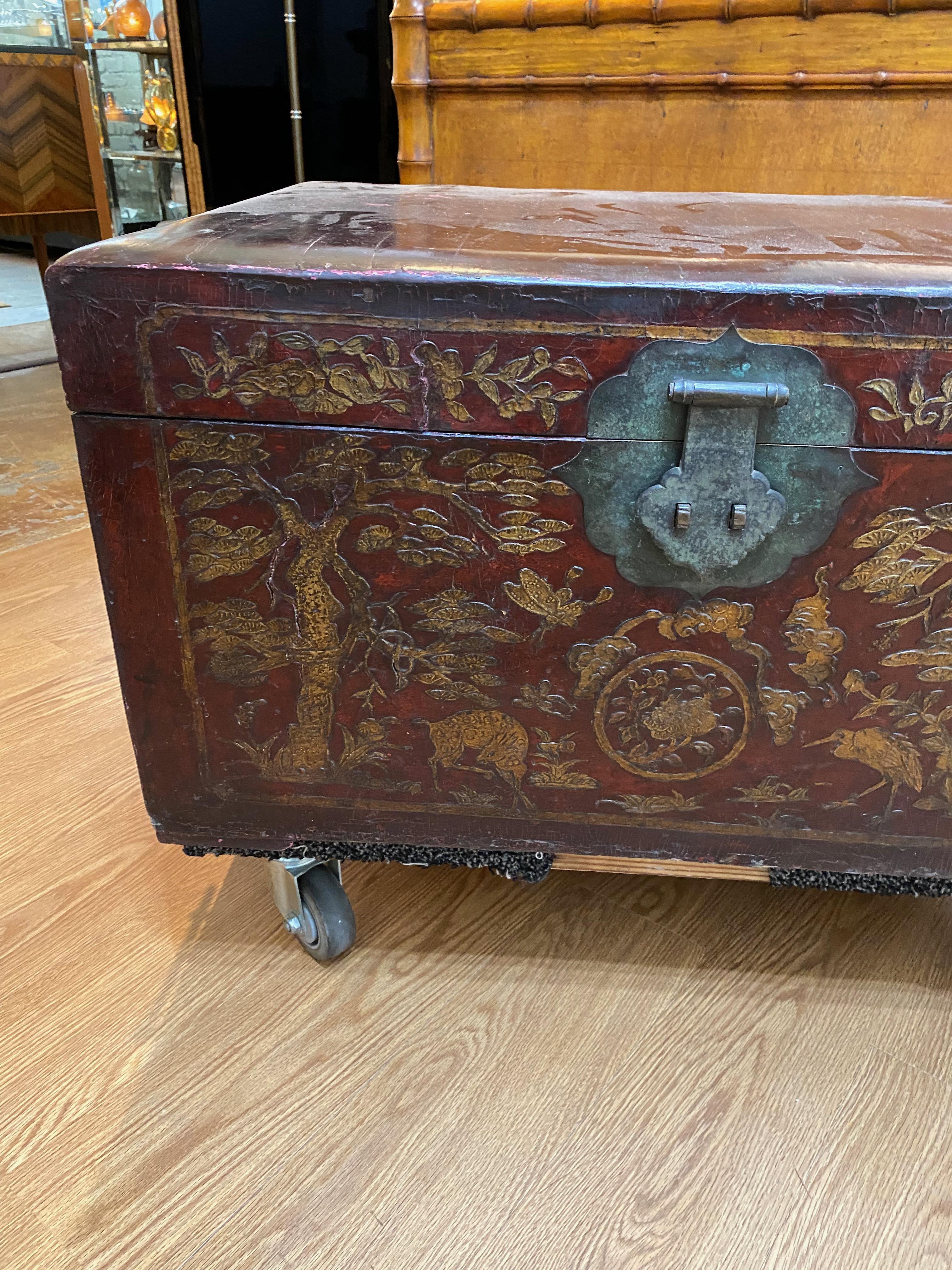 This is an unusual large Chinese tooled leather trunk that dates to the late 19th or early 20th century. The front face of the trunk is detailed in tooled traditional symbols of Chinese good fortune--deer, flowering trees, butterflies, cranes, etc.