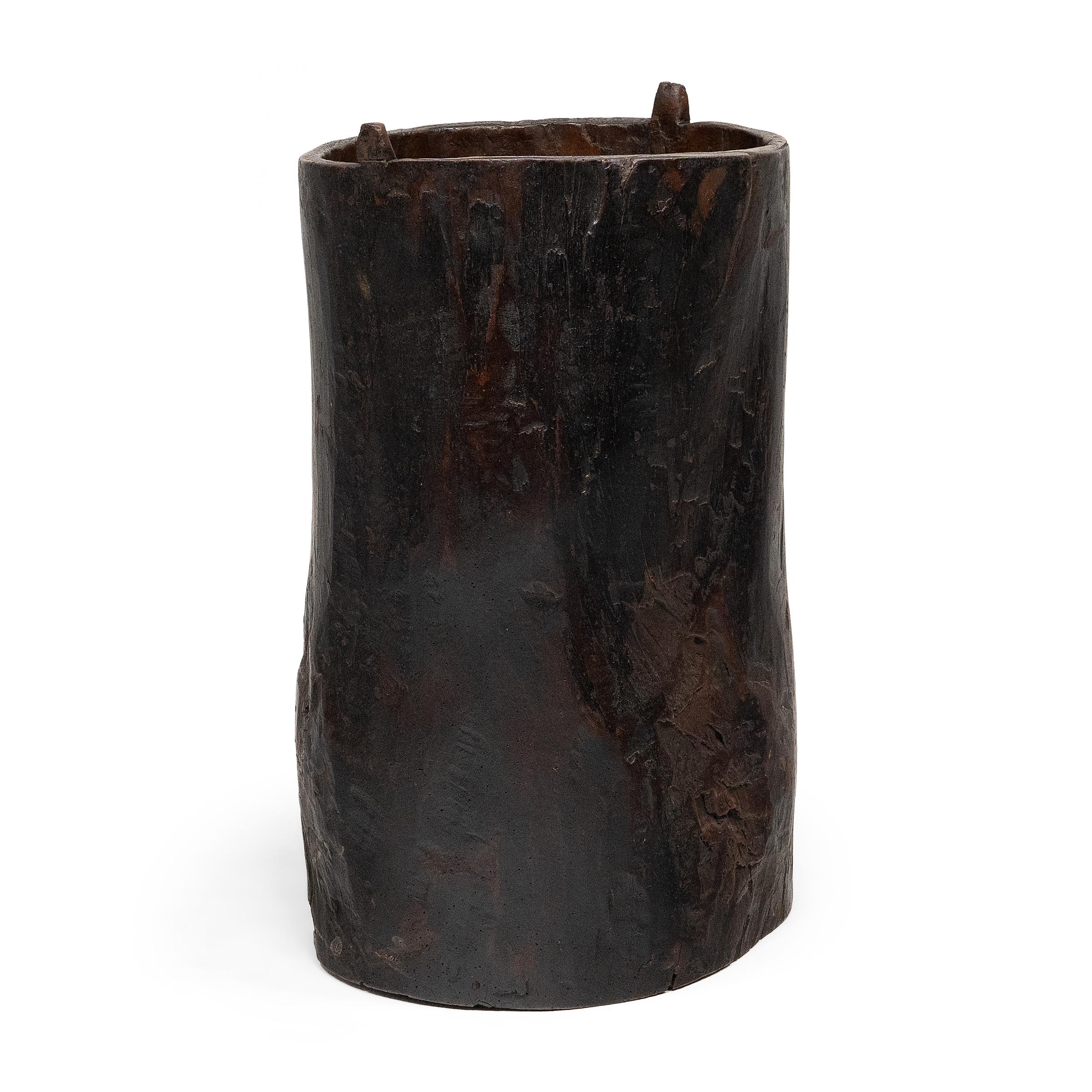 This hand-crafted wooden container dates to the mid-19th century and was likely used to store various foods or household items. Darkened by a rich patina, the container is elegantly constructed from a single block of wood with a beautifully active