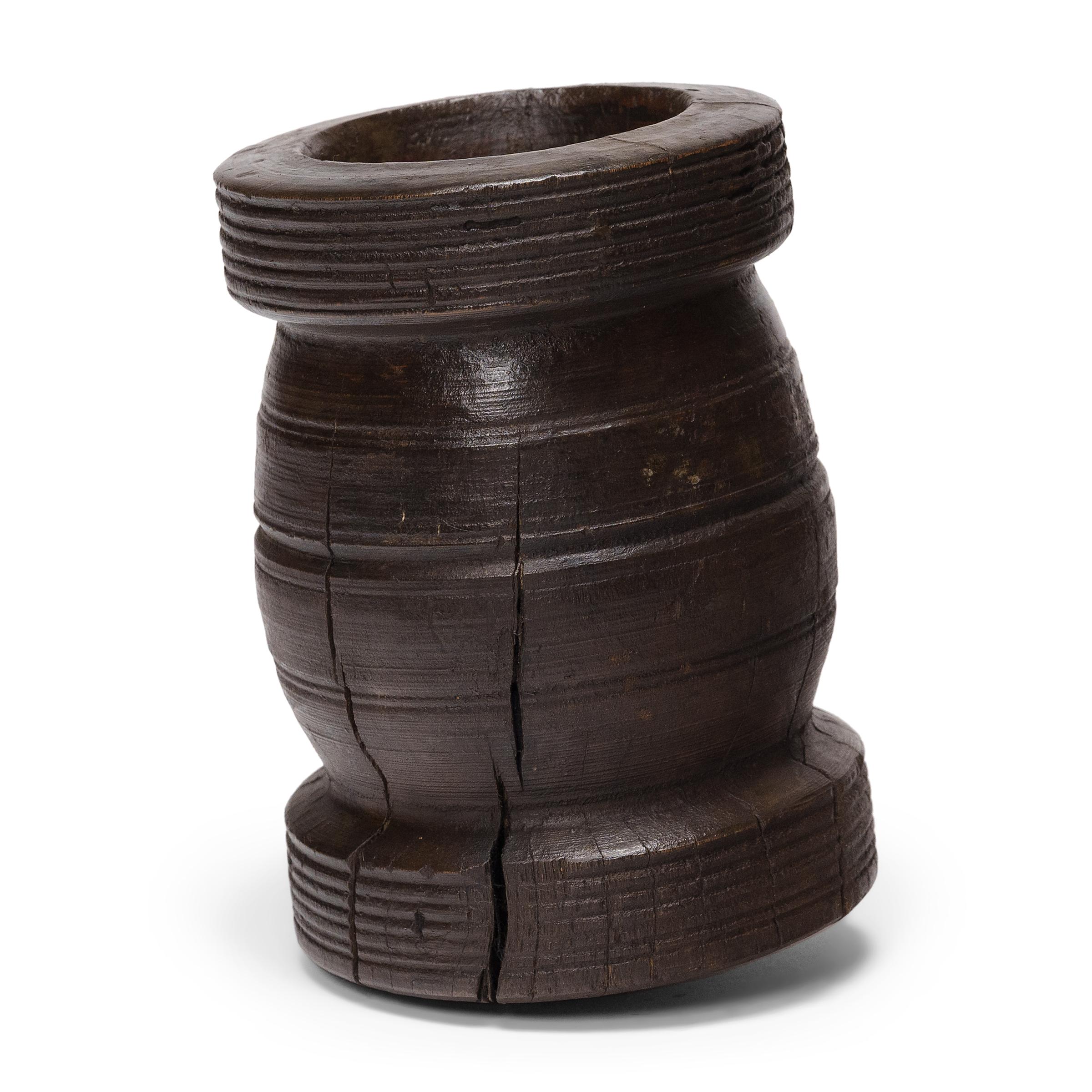 Este pequeño recipiente de madera de pino es un mortero de principios del siglo XX que se utilizaba a diario en una cocina provinciana para moler hierbas, especias y condimentos. El recipiente rústico fue torneado a mano con forma de balaustre