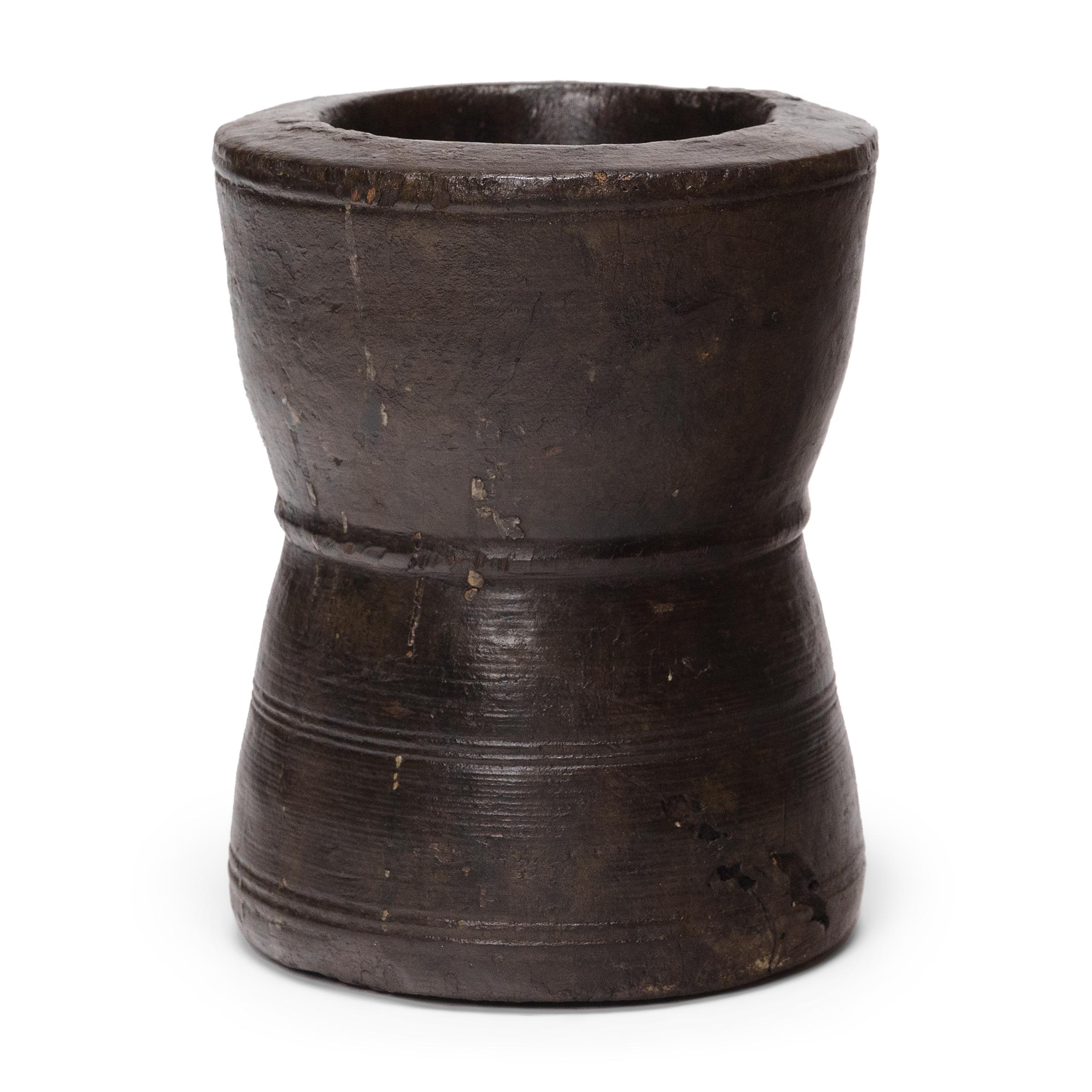 Questo piccolo recipiente in legno di pino è un mortaio dell'inizio del XX secolo, un tempo utilizzato quotidianamente in una cucina di provincia per macinare erbe, spezie e condimenti. Il contenitore rustico è stato tornito a mano a forma di