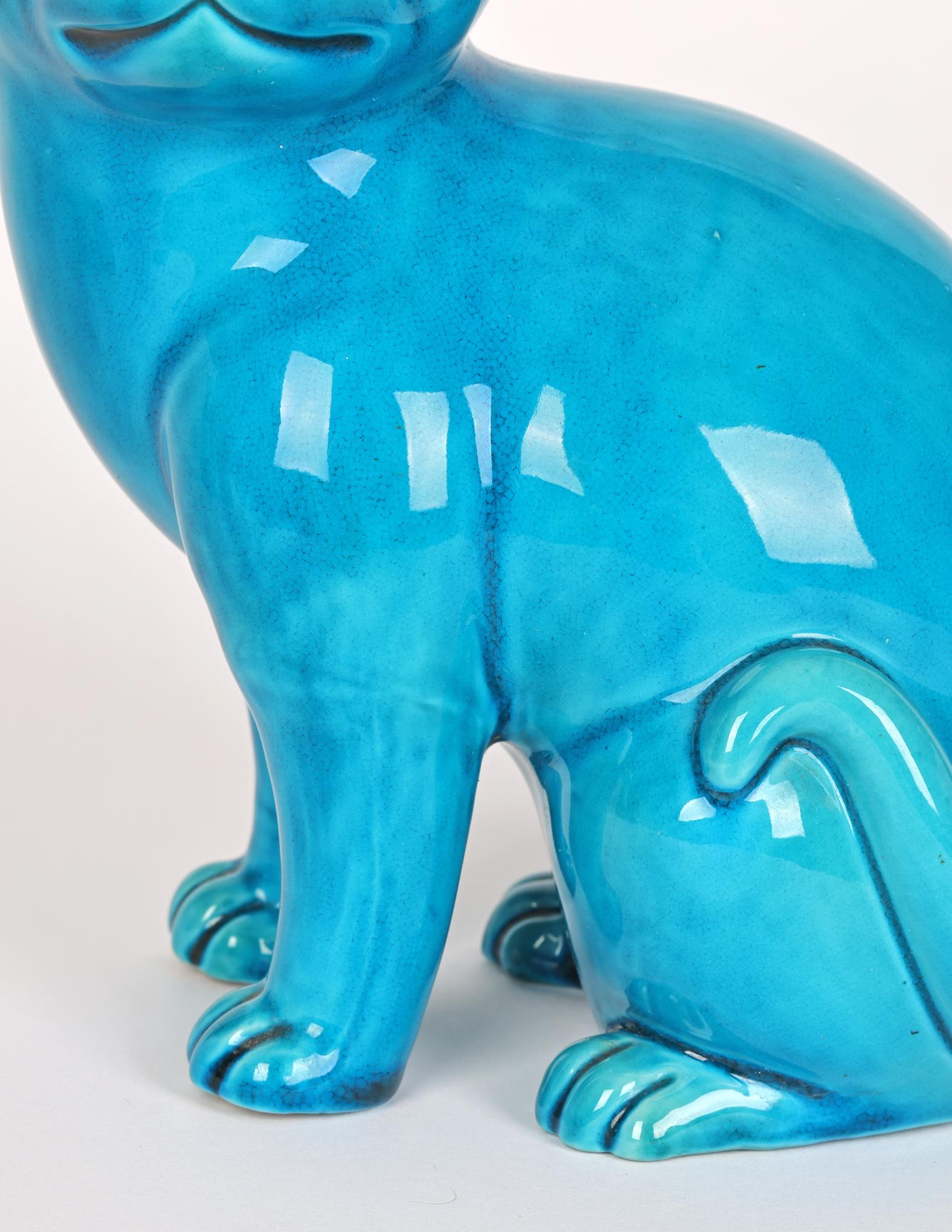 A very stylish Chinese porcelain figure of a seated cat decorated in bright turquoise glazes and dating from around 1920. The large seated cat is well modelled and sits glancing sideways with its tail resting on its back leg and with its ears raised