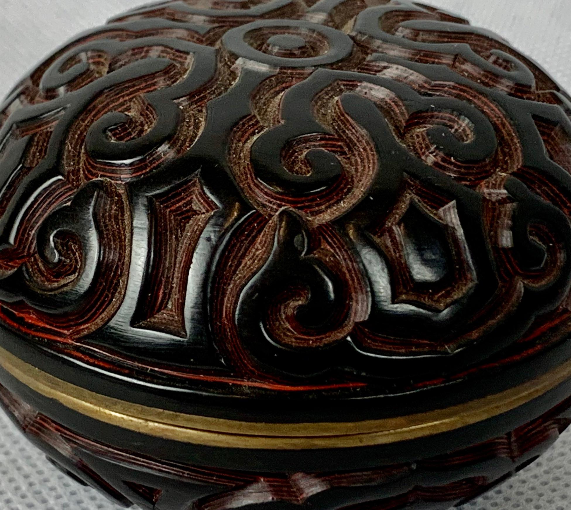 This is a Chinese two color Tixi cinnabar box or jar. Created early in the twentieth century with a stylized symbol design, black interior and brass collar. What makes this piece so interesting is the many layers of lacquer and very deep carving,