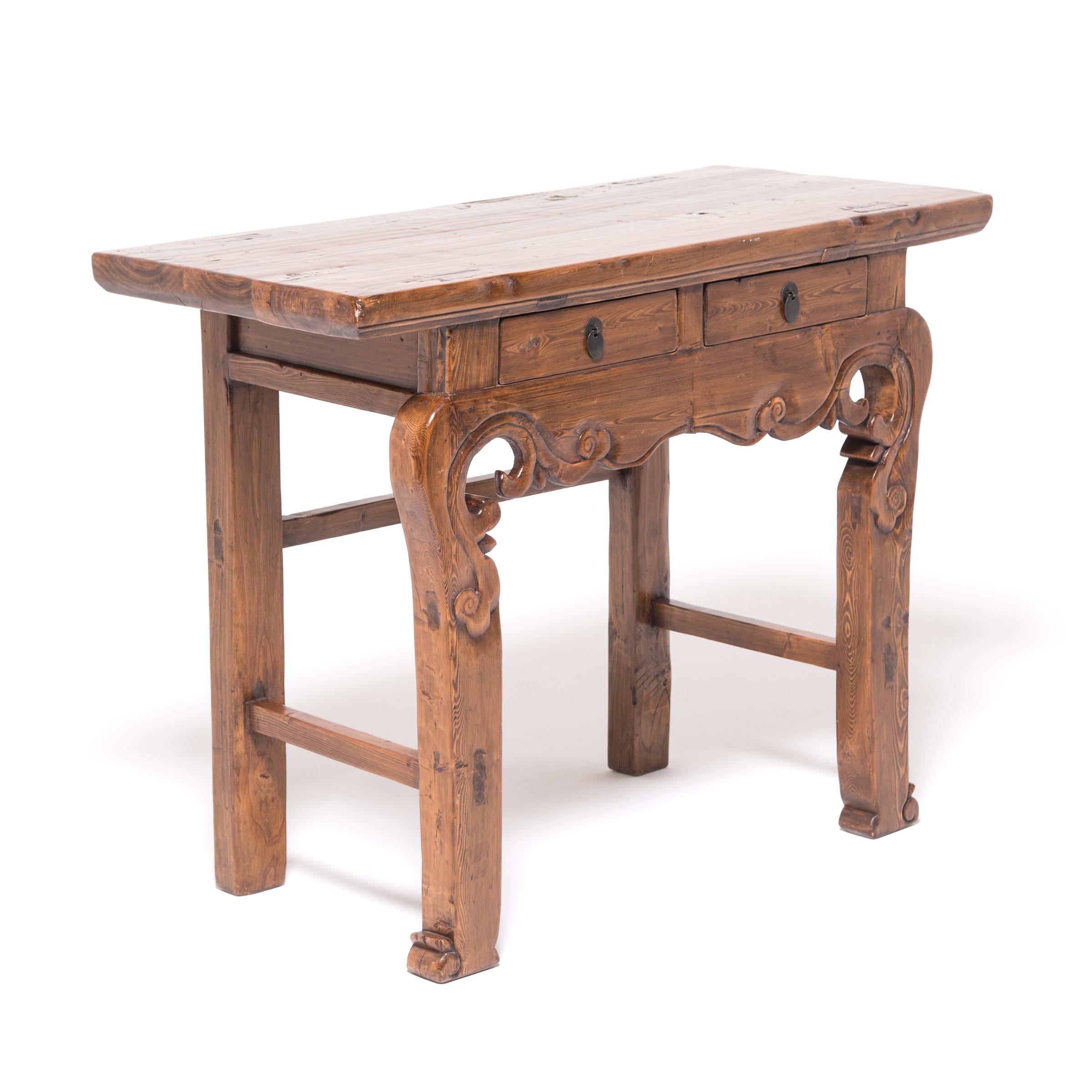 The pronounced grain and warm color of golden pine are wonderfully displayed in the artful carvings of this beautifully proportioned altar table. Expressive scrollwork articulates the table’s graceful flow from apron to leg to feet, marked by