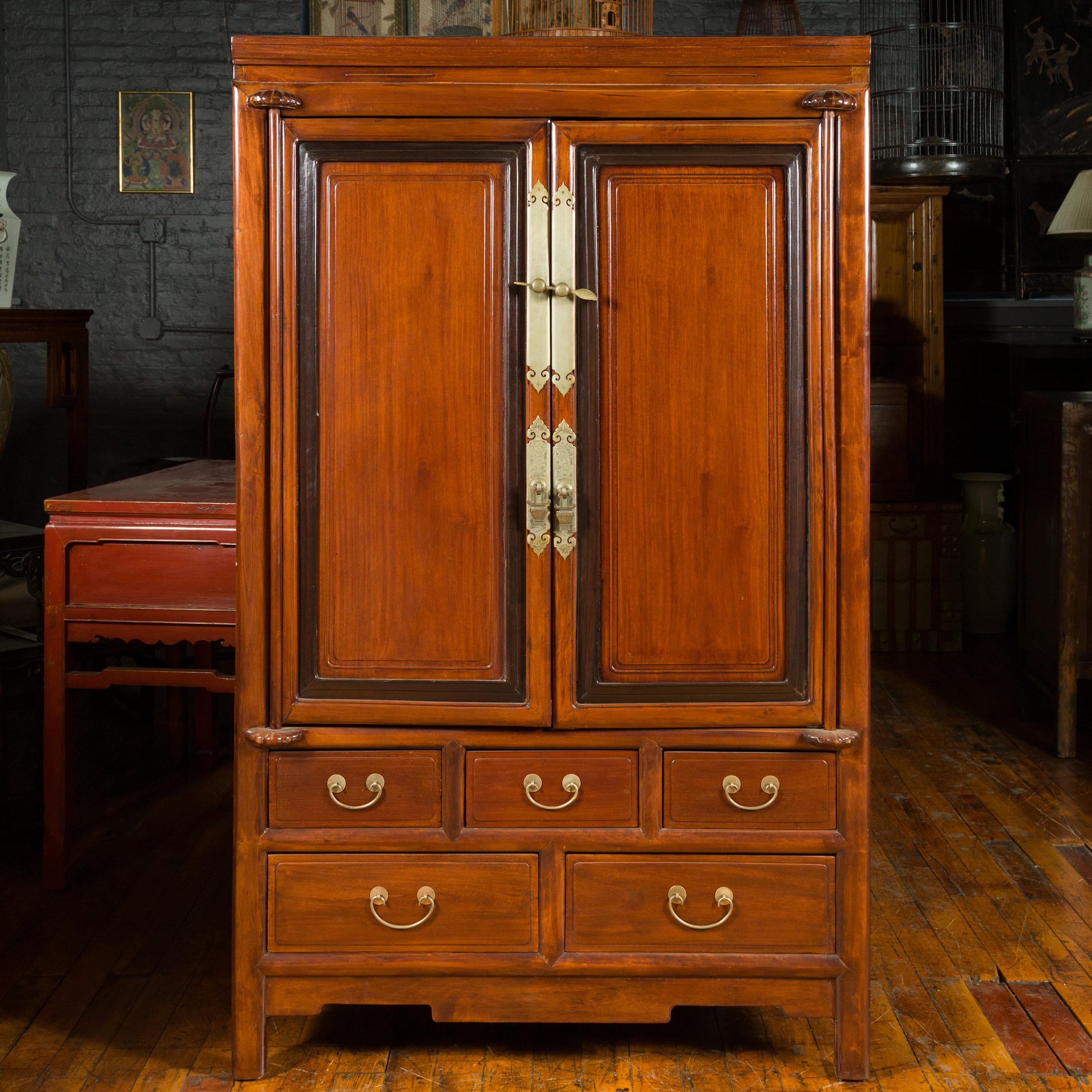 A two-toned cabinet from the 20th century, with doors and drawers. This exquisite two-toned cabinet from the 20th century features a harmonious blend of style and functionality. The tall structure showcases two doors adorned with dark inner molding,