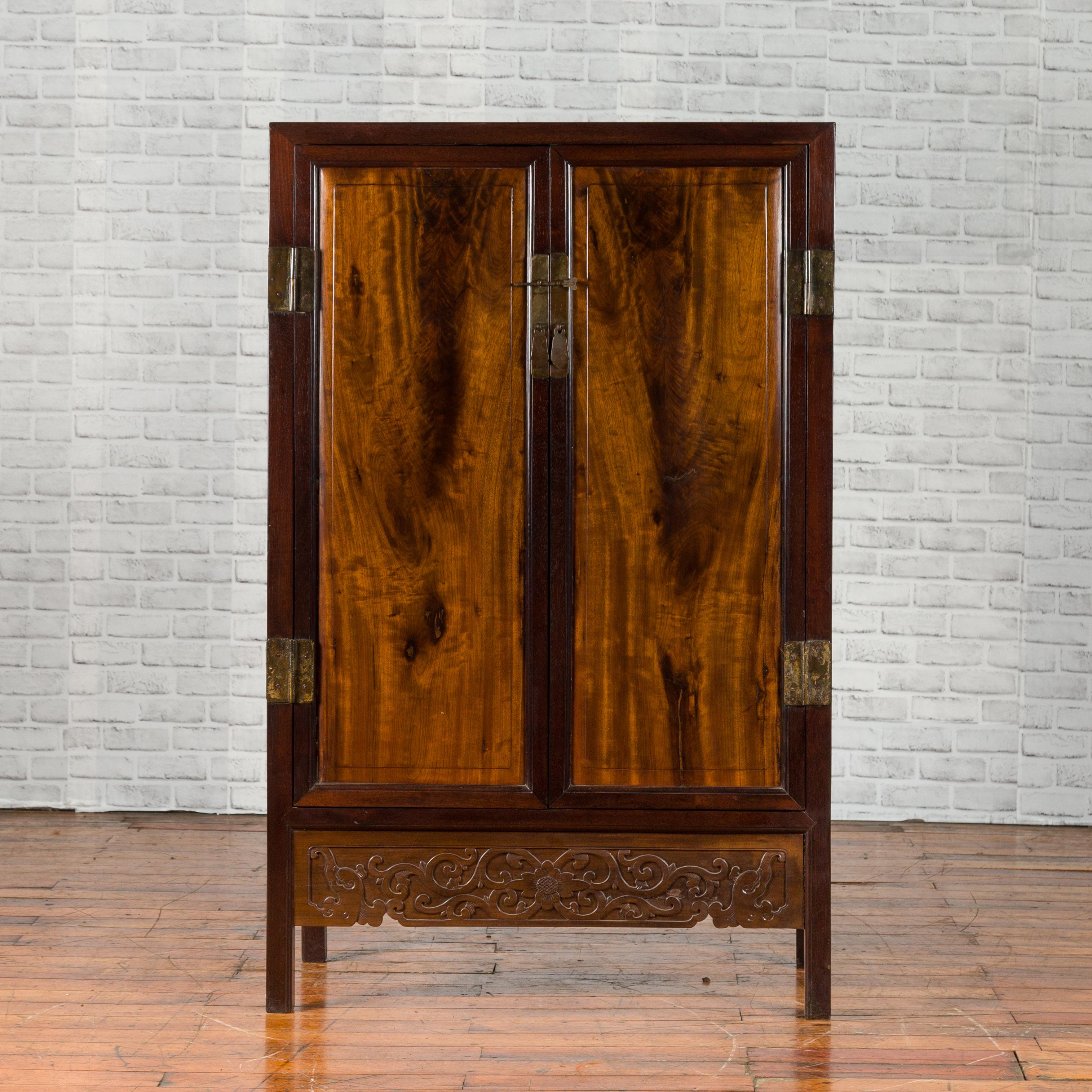 A Chinese dark wood cabinet from the early 20th century with two-toned panels and carved apron. Created in China during the early years of the 20th century, this cabinet features a linear silhouette perfectly accented by a two-toned finish. The dark