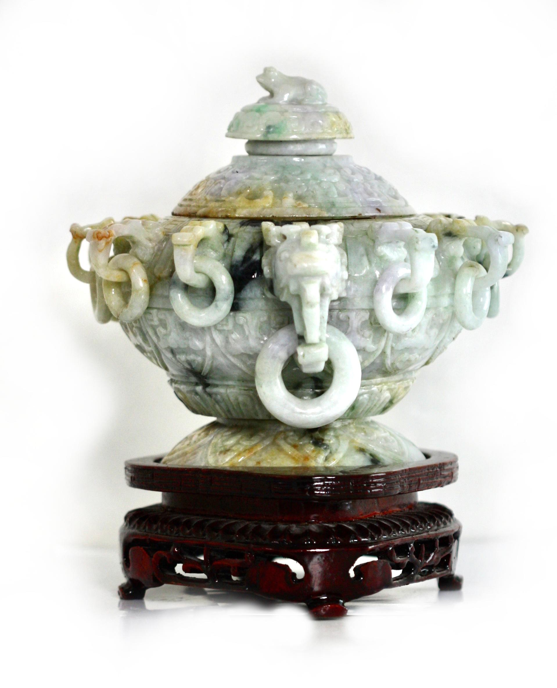 
Chinese Unusual Multi-Colored Jade Covered Bowl/Censor. 
The circular body with two projecting dragon mask handles with loose rings and with ten additional projecting stylized masks also with loose rings, the circular knopped cover with a frog