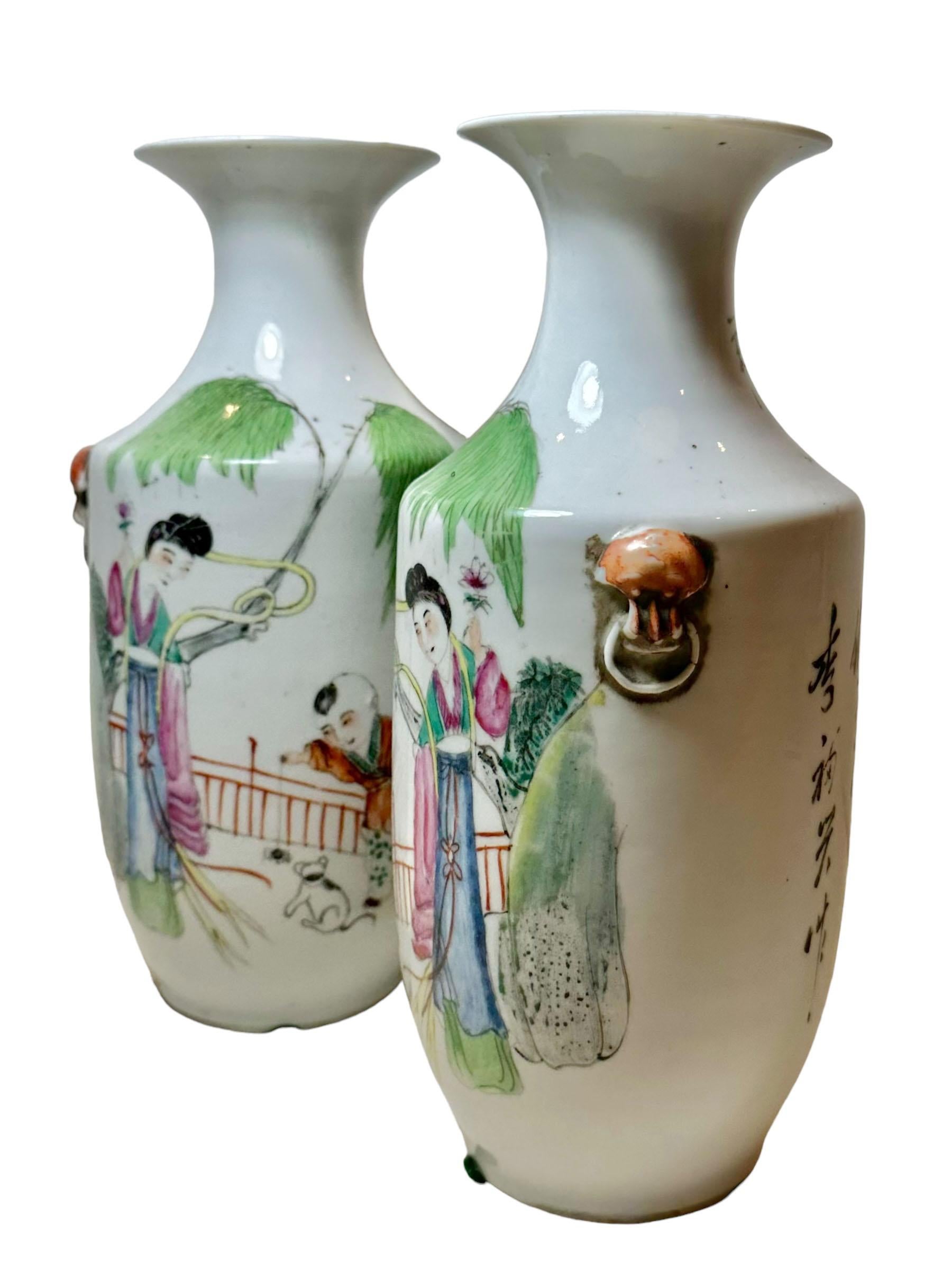Questi splendidi vasi cinesi, risalenti al 1900, sono un'affascinante miscela di arte e tradizione. Il vaso raffigura una tenera scena di madre e figlio che giocano con un cane. Su entrambi i lati gli animali tengono in bocca degli anelli,