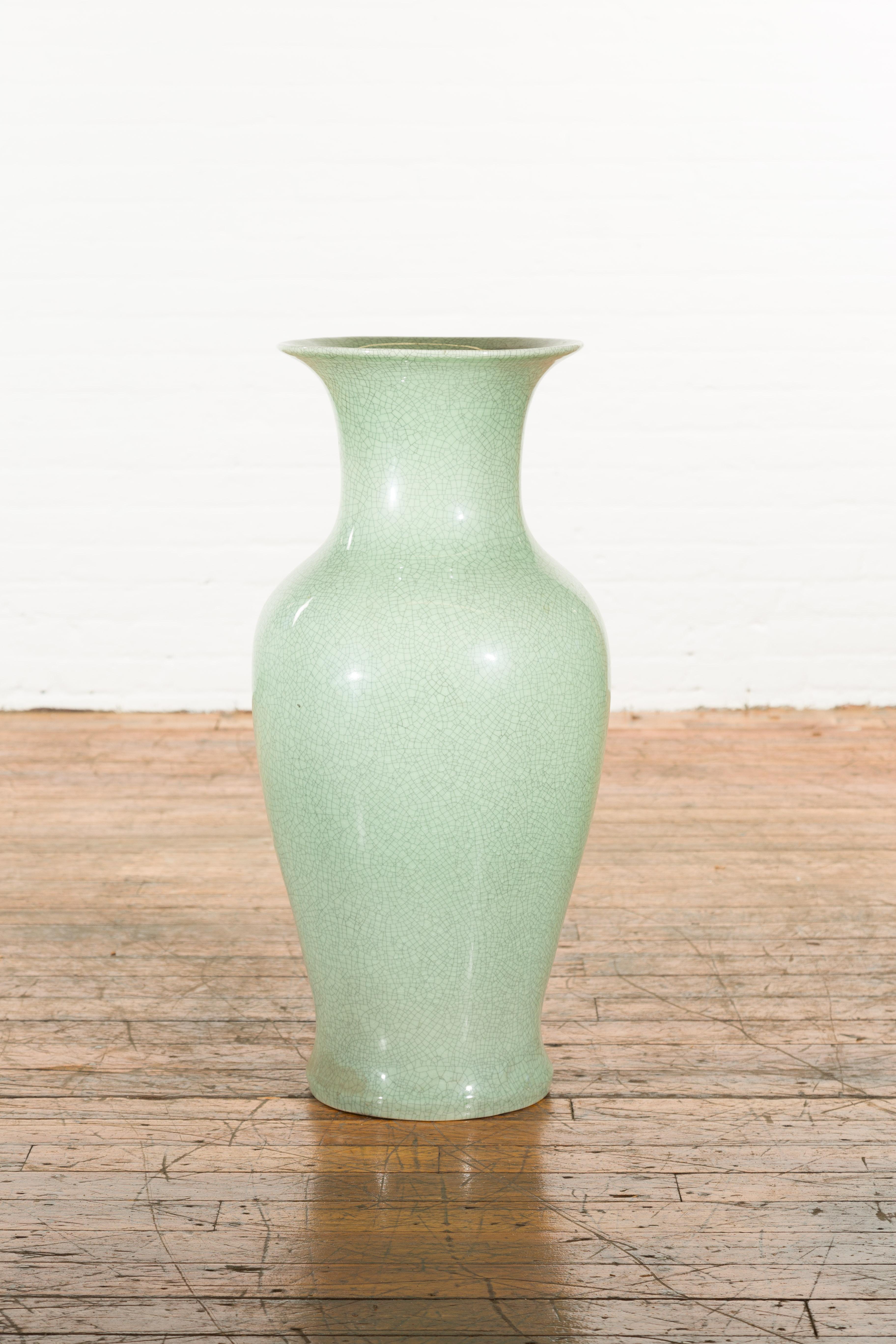 A Chinese vintage altar vase from the mid 20th century, with celadon crackle finish and flaring neck. We currently have 3 vases available, priced and sold $1,300 each. Created in China during the midcentury period, this tall altar vase charms us