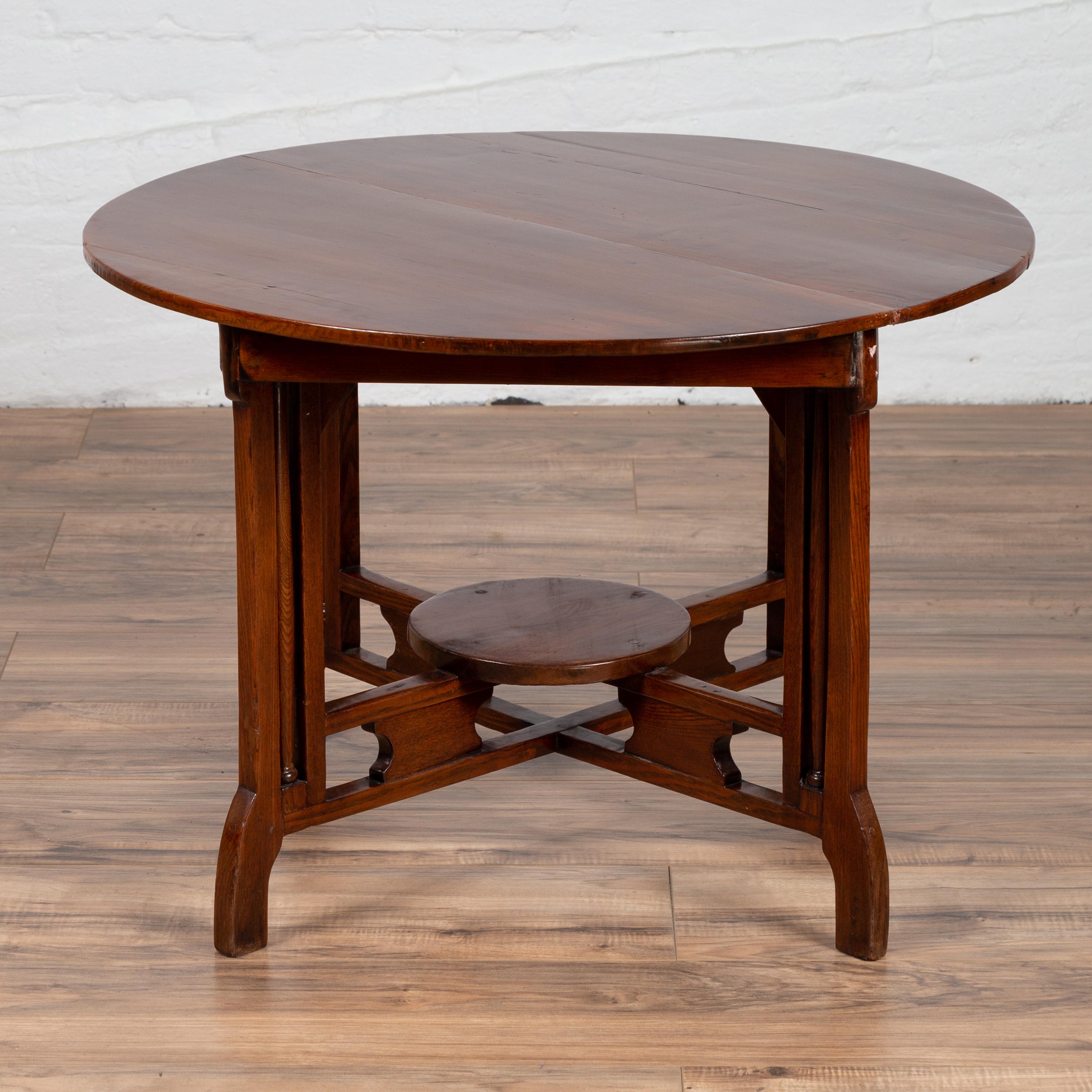 A vintage Chinese Art Deco style side table from the mid 20th century, with brown lacquer, round top and unusual base. Born in China during the midcentury period, this Chinese table presents the stylistic characteristics of the Art Deco style.