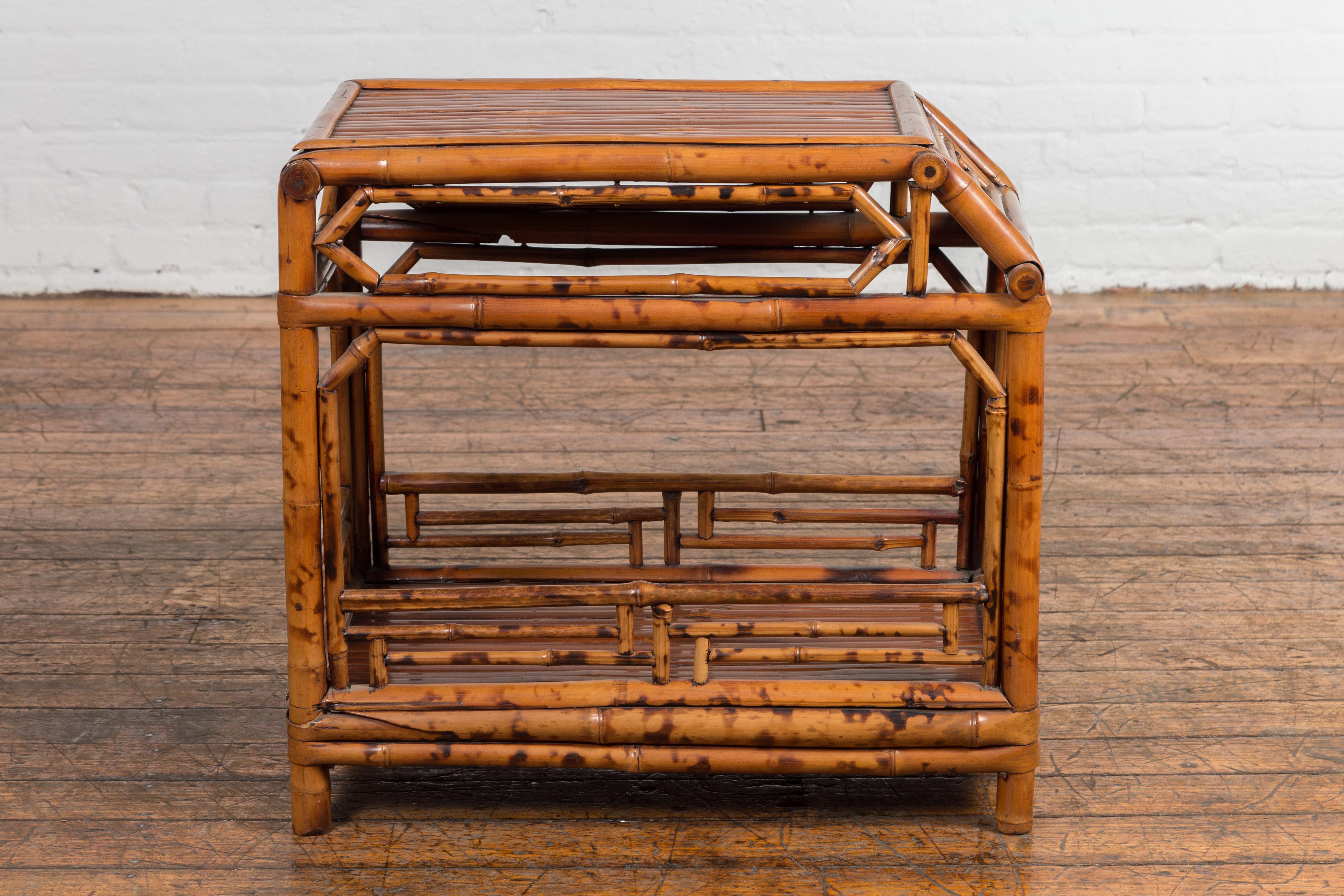 A vintage Chinese bamboo side table from the mid 20th century with fretwork motifs, natural stain finish. Exemplifying mid 20th-century Chinese craftsmanship, this vintage bamboo side table is a combination of simple elegance and thoughtful design.