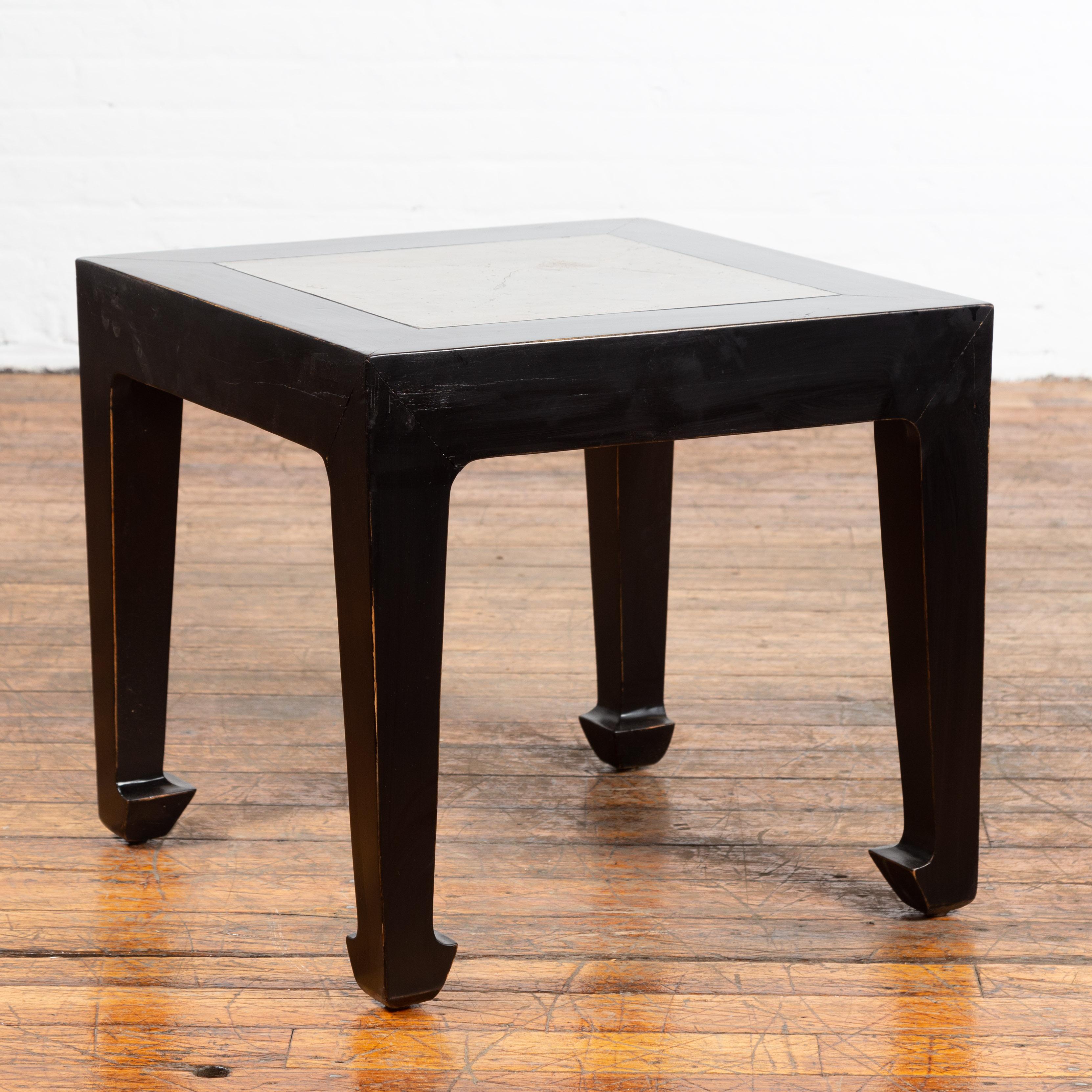 A Chinese vintage black lacquer side table from the mid-20th century with antique Qing Dynasty 19th century stone inset and horse hoof legs. Created in China during the midcentury period, this black lacquer side table features an exquisite grey hued