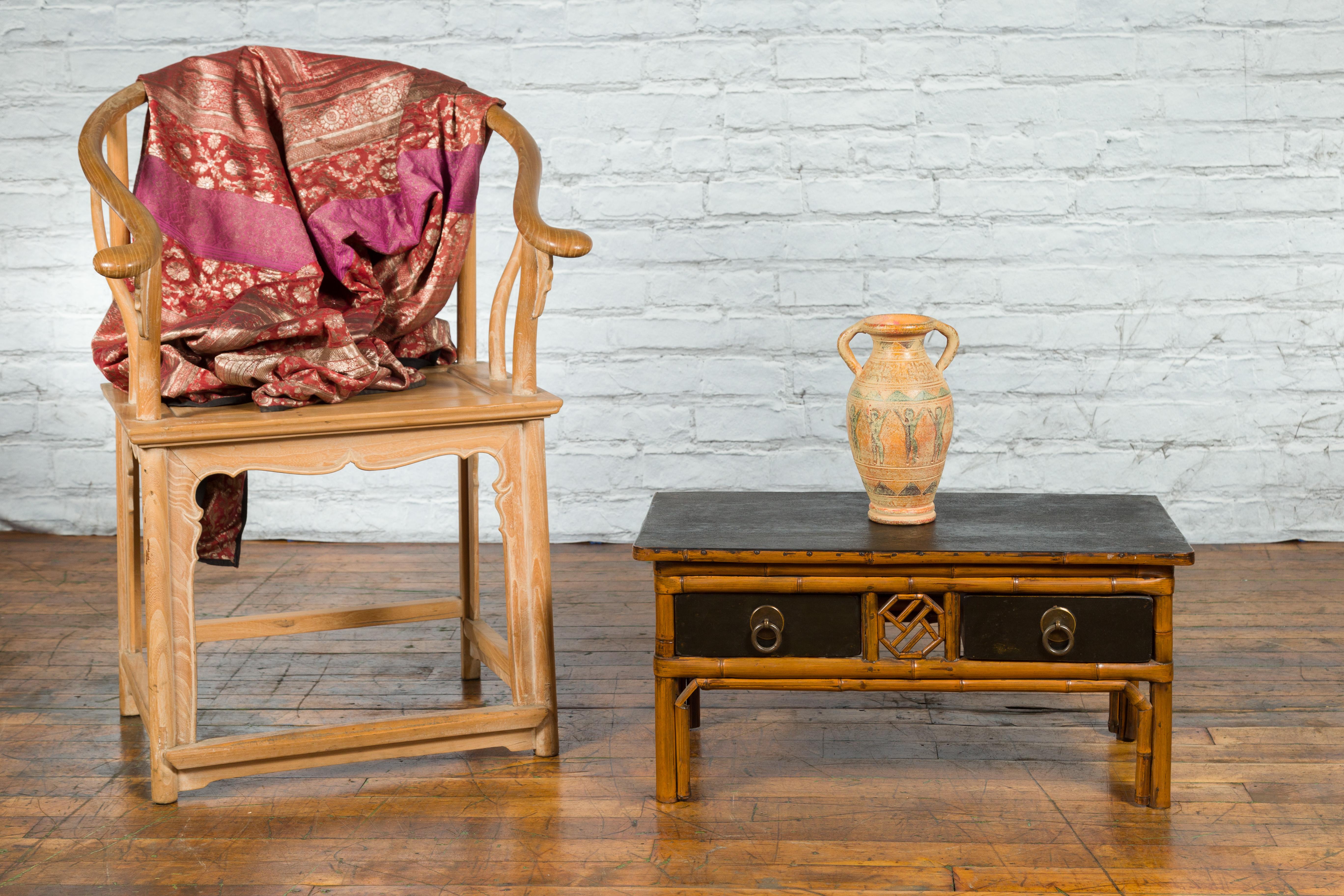 A vintage Chinese black lacquered elm and bamboo side table from the mid 20th century, with fretwork motifs and two drawers. Created in China during the midcentury period, this two-toned elm and bamboo side table features a rectangular black top