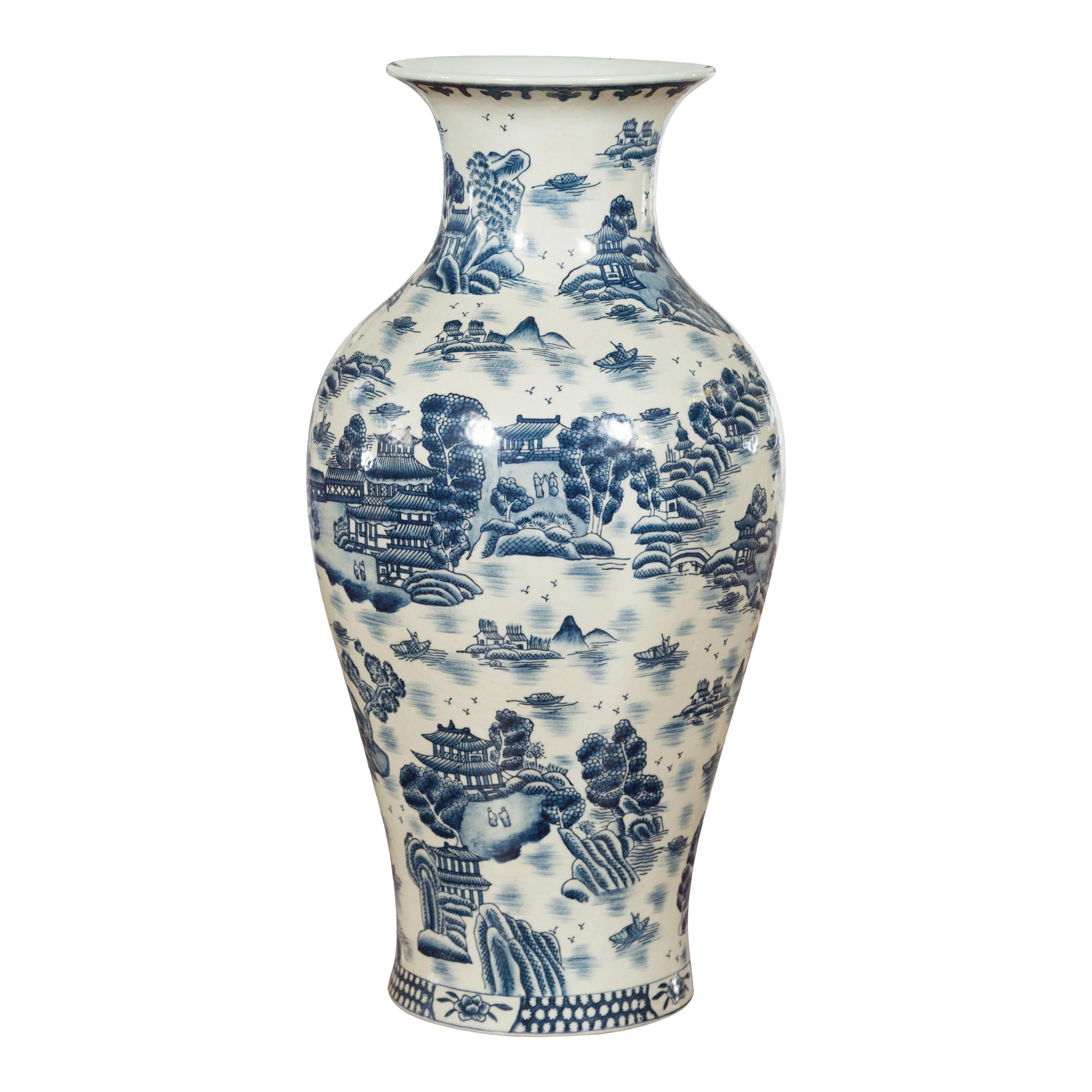 A vintage Chinese blue and white hand-painted vase from the mid-20th century, with architecture, tree and water décor. Created in China during the Midcentury period, this porcelain vase features a nicely curving silhouette topped with a narrow neck