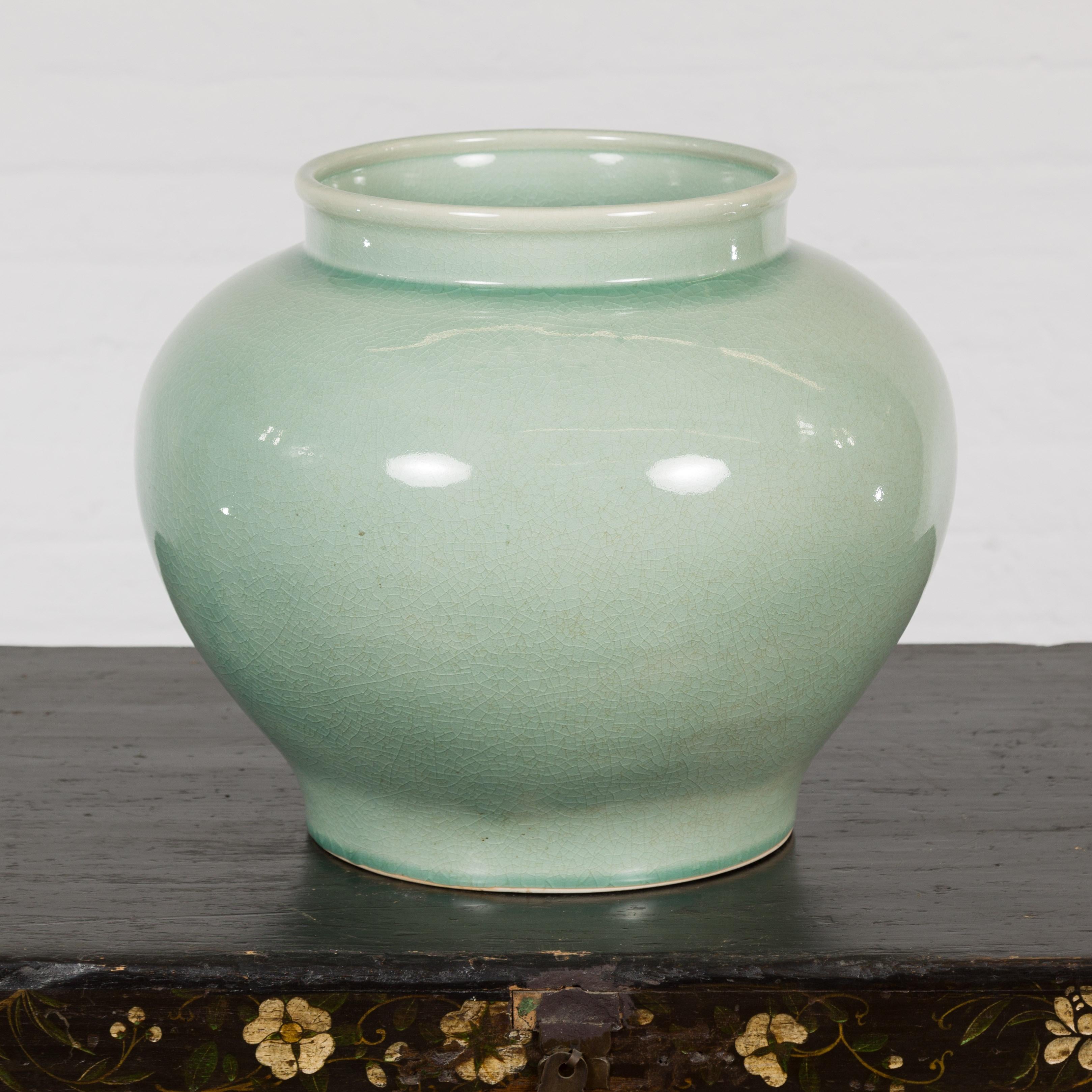 A vintage Chinese celadon color garden planter from the mid 20th century with crackle glaze, circular opening and generous tapering lines. Elevate your indoor or outdoor space with this vintage Chinese celadon garden planter from the mid-20th
