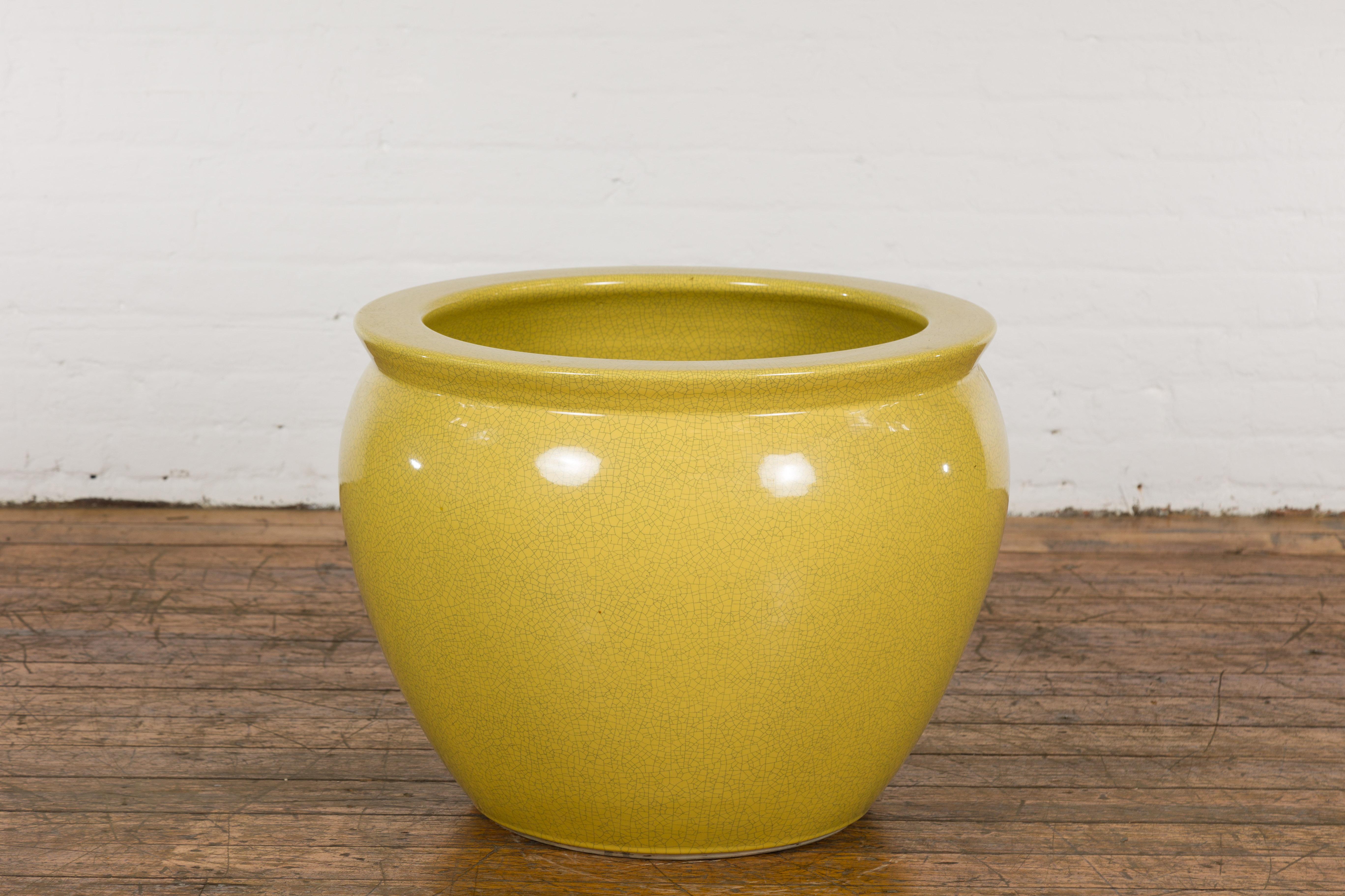 A vintage Chinese round garden planter from the mid 20th century, with yellow crackle finish and beveled lip. Created in China during the midcentury period, this vintage Chinese garden planter features a circular shape topped with a lip showcasing a