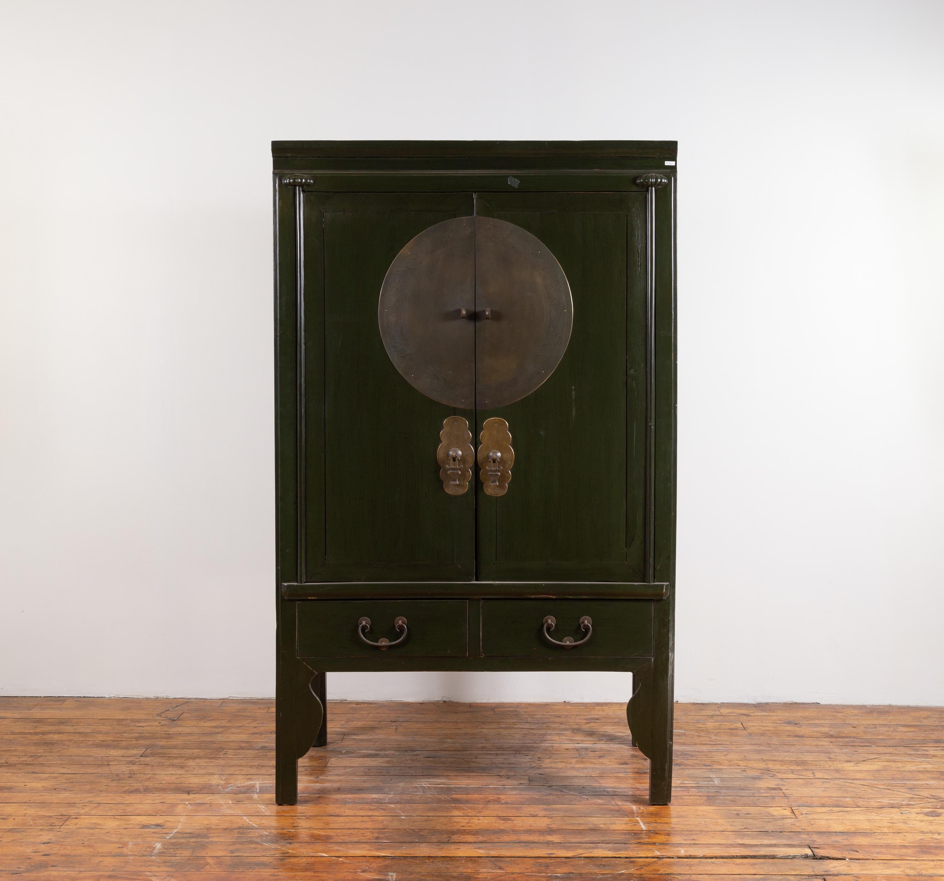 A vintage Chinese Ming dynasty dark green wedding cabinet from the mid-20th century, with two doors over two drawers. Born in China during the mid-century period, this exquisite wedding cabinet features two doors, beautifully accented with a