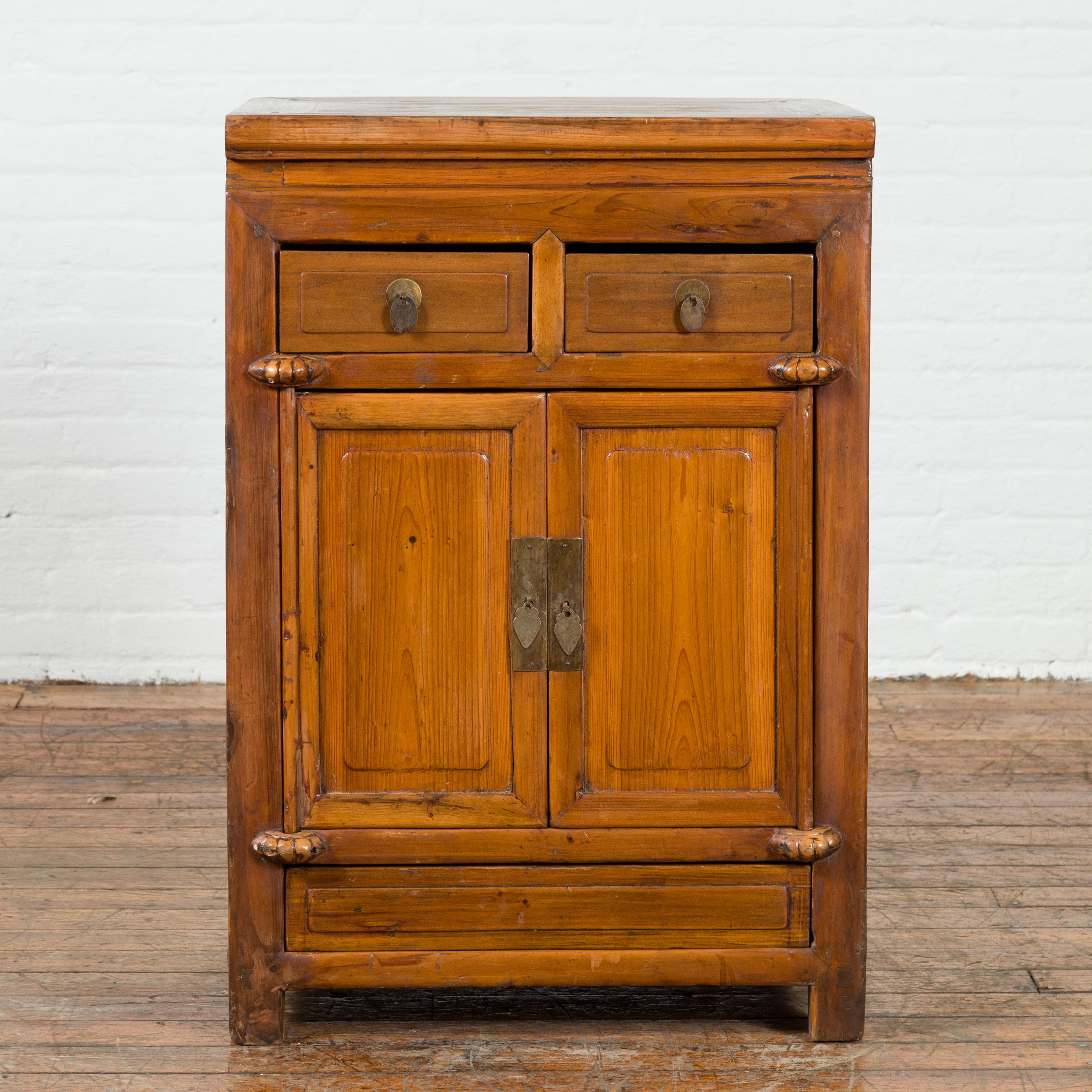 A vintage Chinese elmwood side cabinet from the mid 20th century with two drawers sitting above two doors. Our mid century vintage cabinet features a rectangular top that offers room for you to style with decorative accent pieces or statuettes. Two
