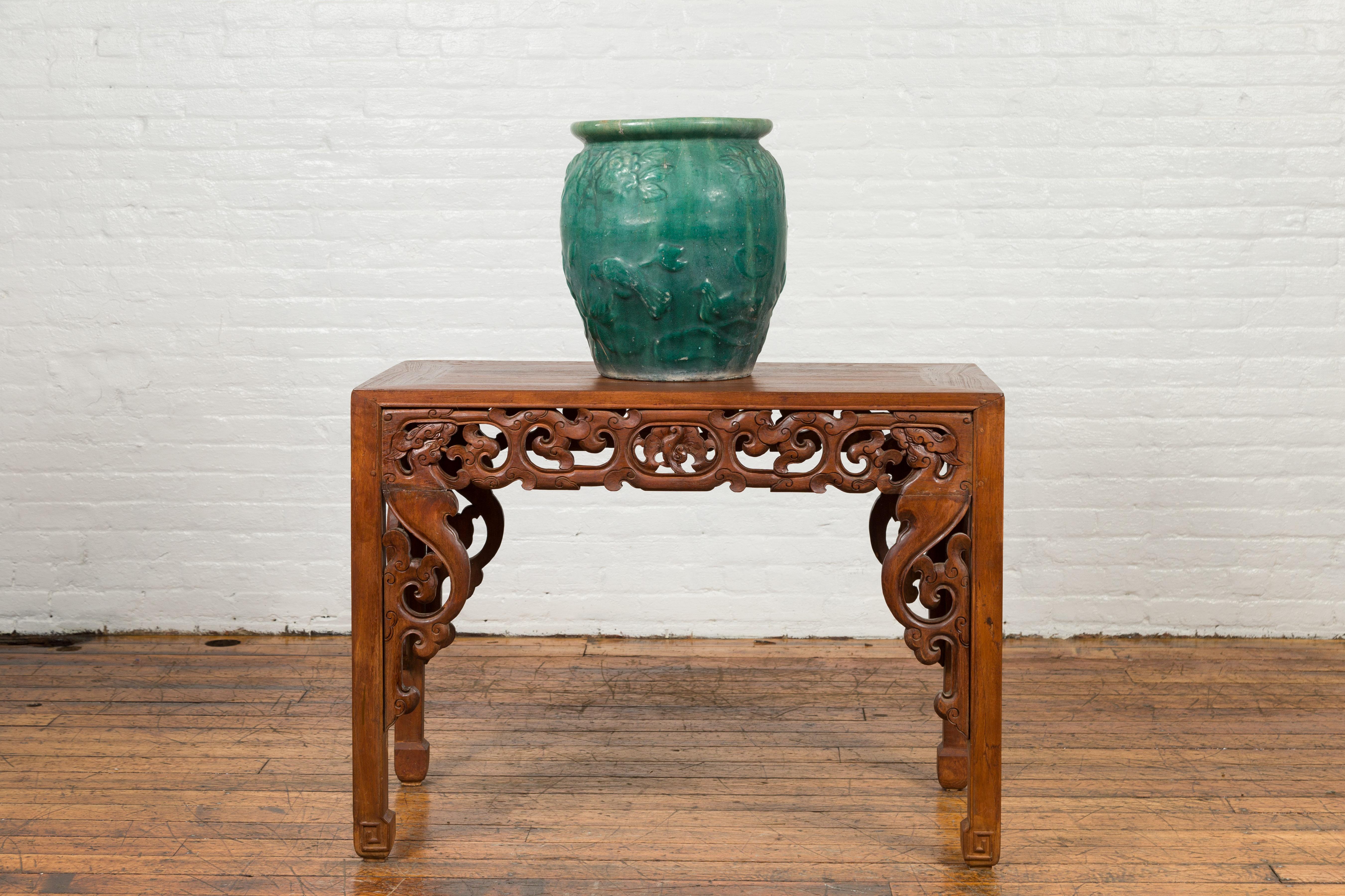 A Chinese vintage green glazed vase from the mid-20th century, with raised floral decor and distressed patina. Created in China during the midcentury period, this flower vase features a green glazed body adorned with raised flowers and birds motifs.