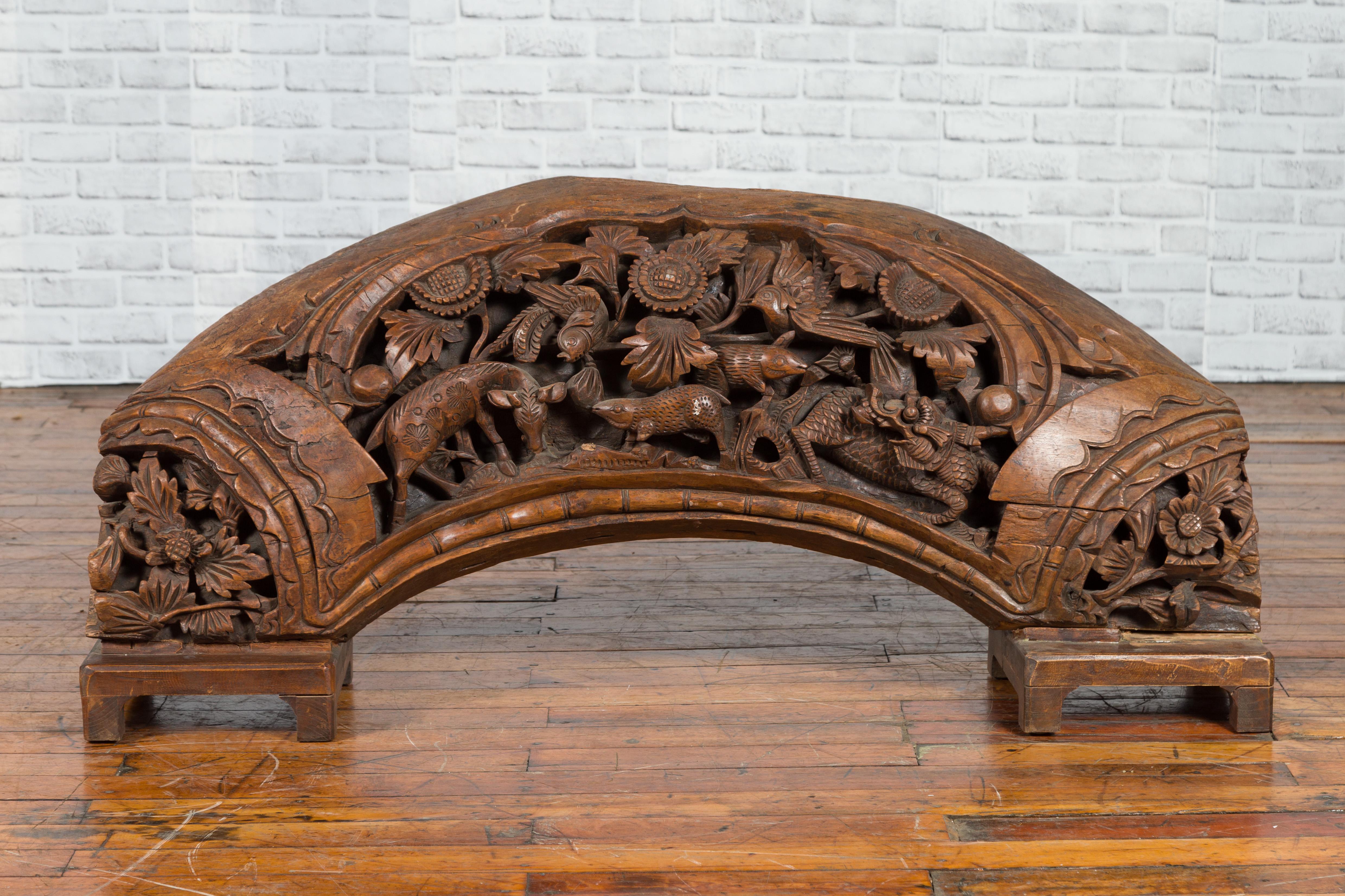 A Chinese vintage hand carved wooden floral and animal carving from the mid-20th century, with arched silhouette. Handcrafted in China and mounted on a custom base, this wooden sculpture depicts various animals and flowers carved in high relief on