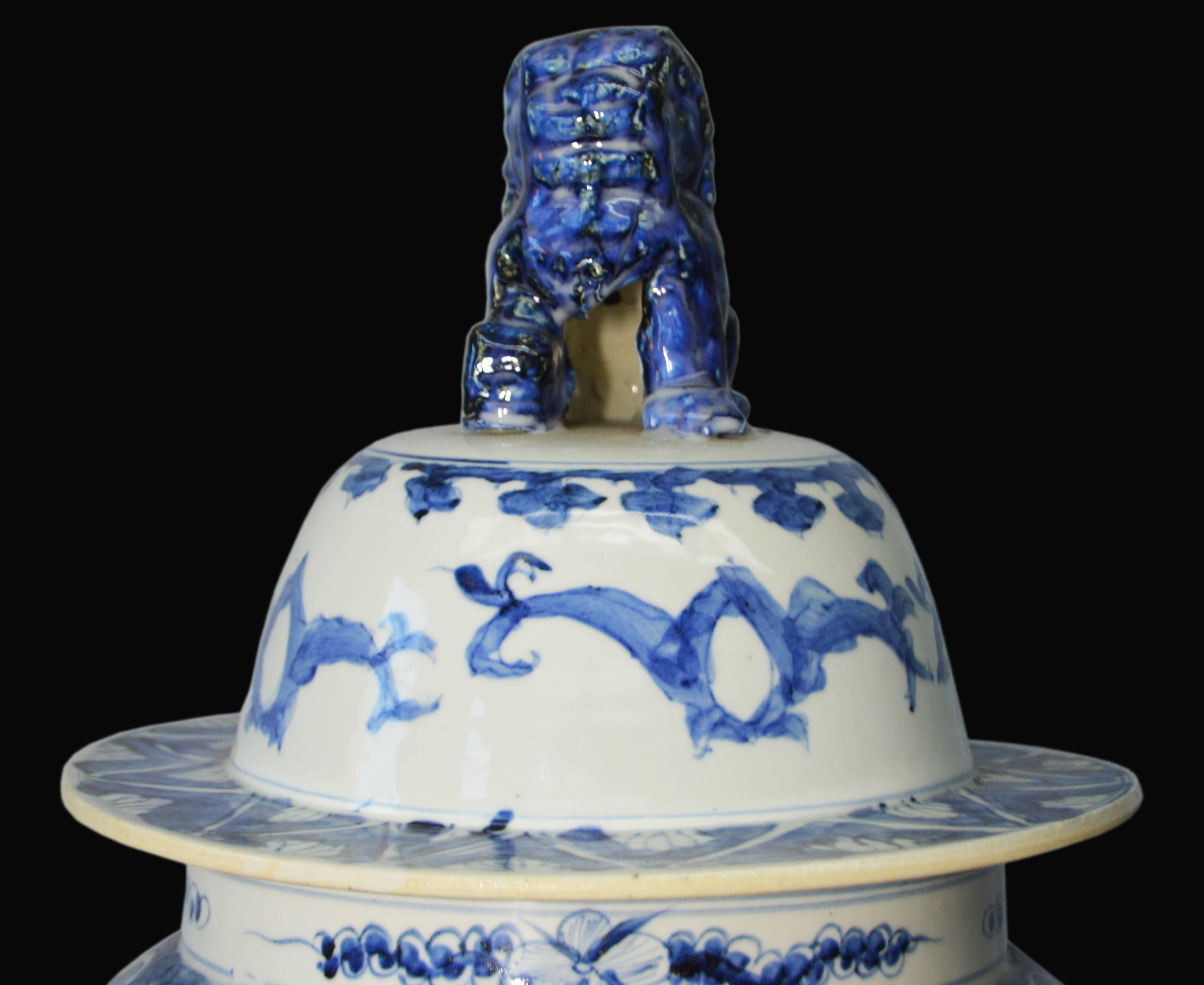 A Chinese vintage hand painted blue and white porcelain vase with dragon motifs and foo-dog lidded top. Born in mid-20th century this Chinese porcelain lidded baluster-form vase features an exquisite blue decor, hand painted on a white ground,