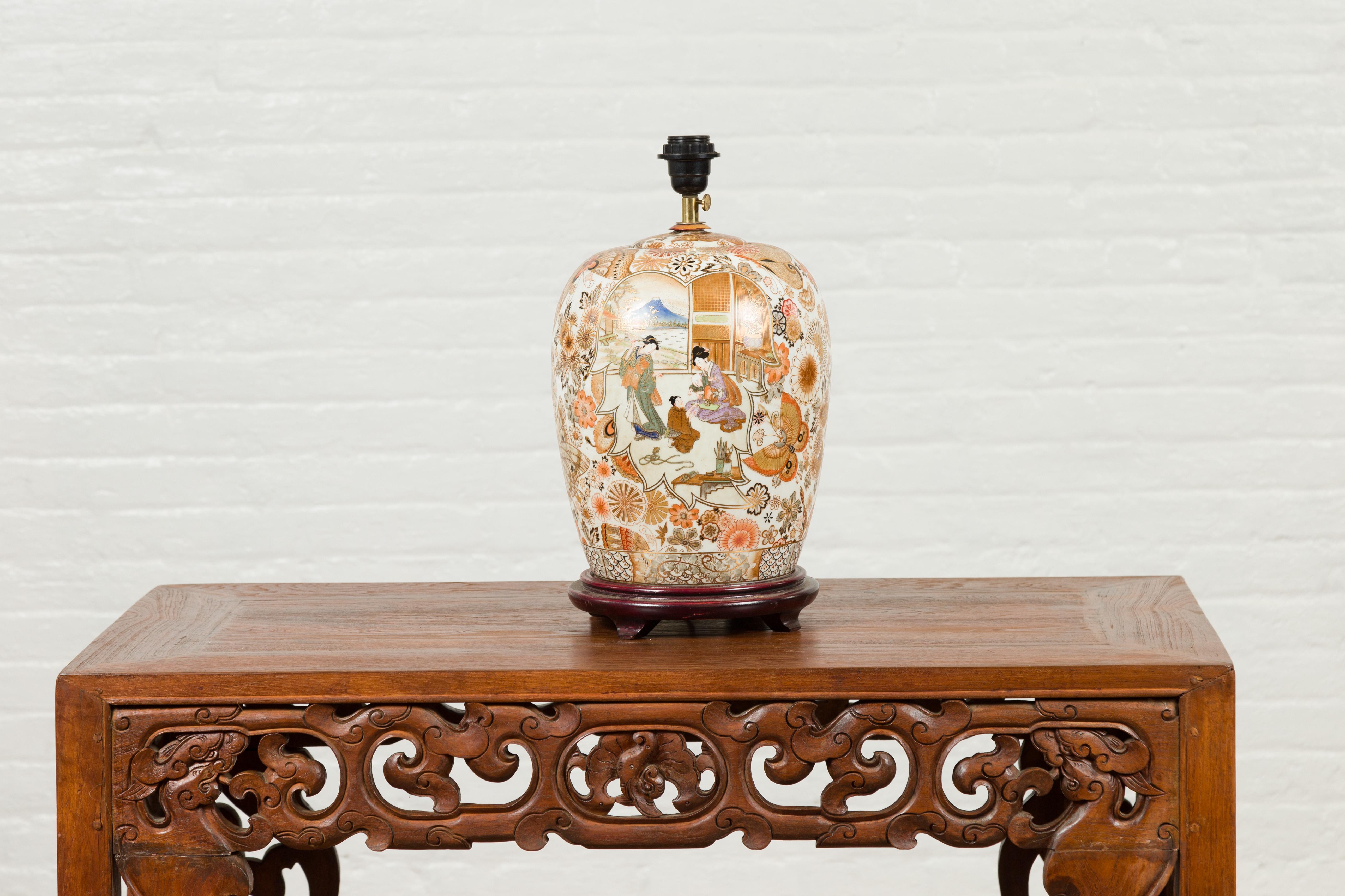 A Chinese vintage Japanese Kutani style lamp from the mid-20th century, with court scenes and wooden base. Crafted in China during the midcentury period, this Kutani style lamp attracts our attention with its orange, golden and brown tones perfectly