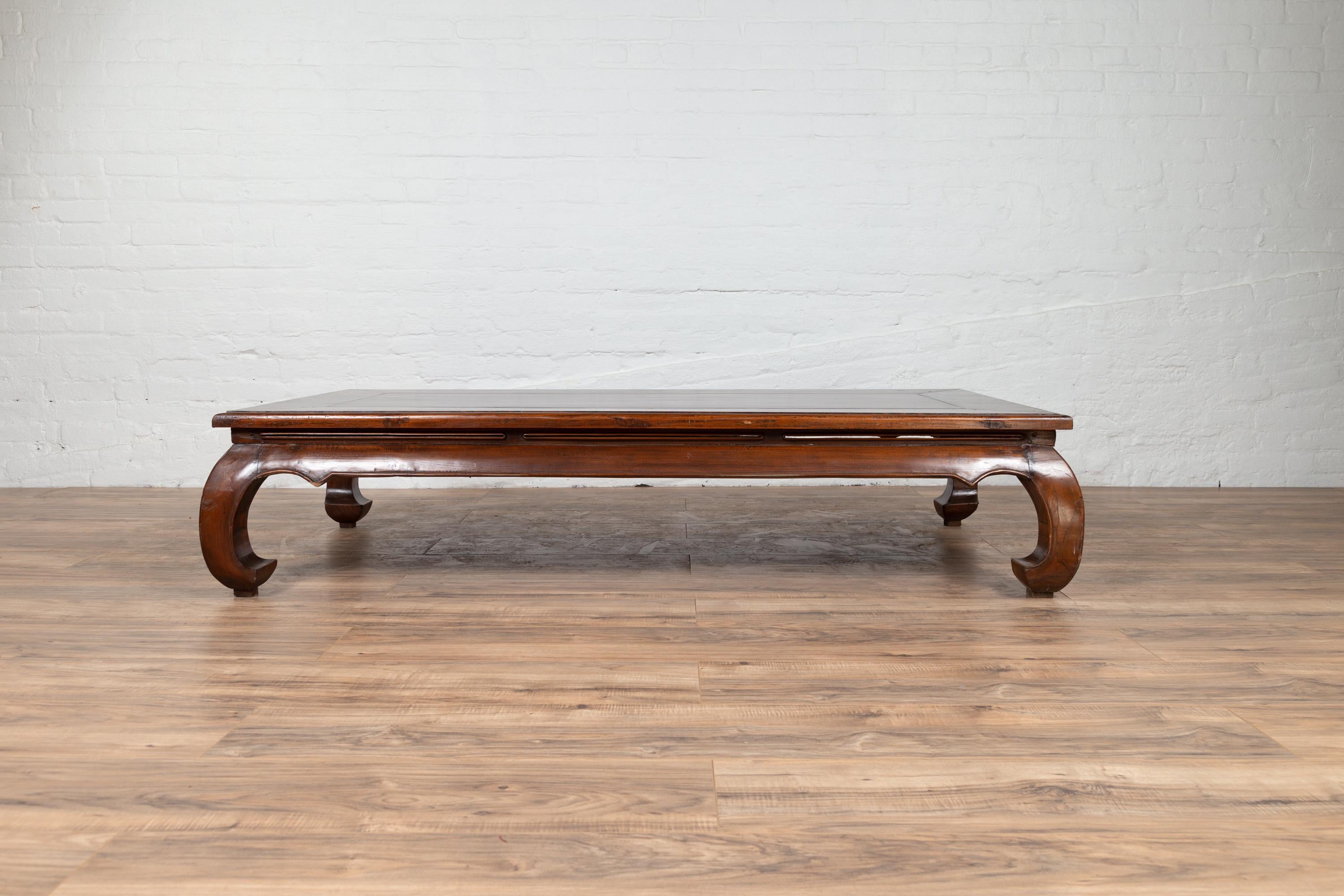 A vintage Chinese long coffee table from the mid-20th century, with chow legs and walnut patina. Born in China during the mid-century period, this large coffee table features a rectangular top with floating panel, sitting above a discreetly pierced