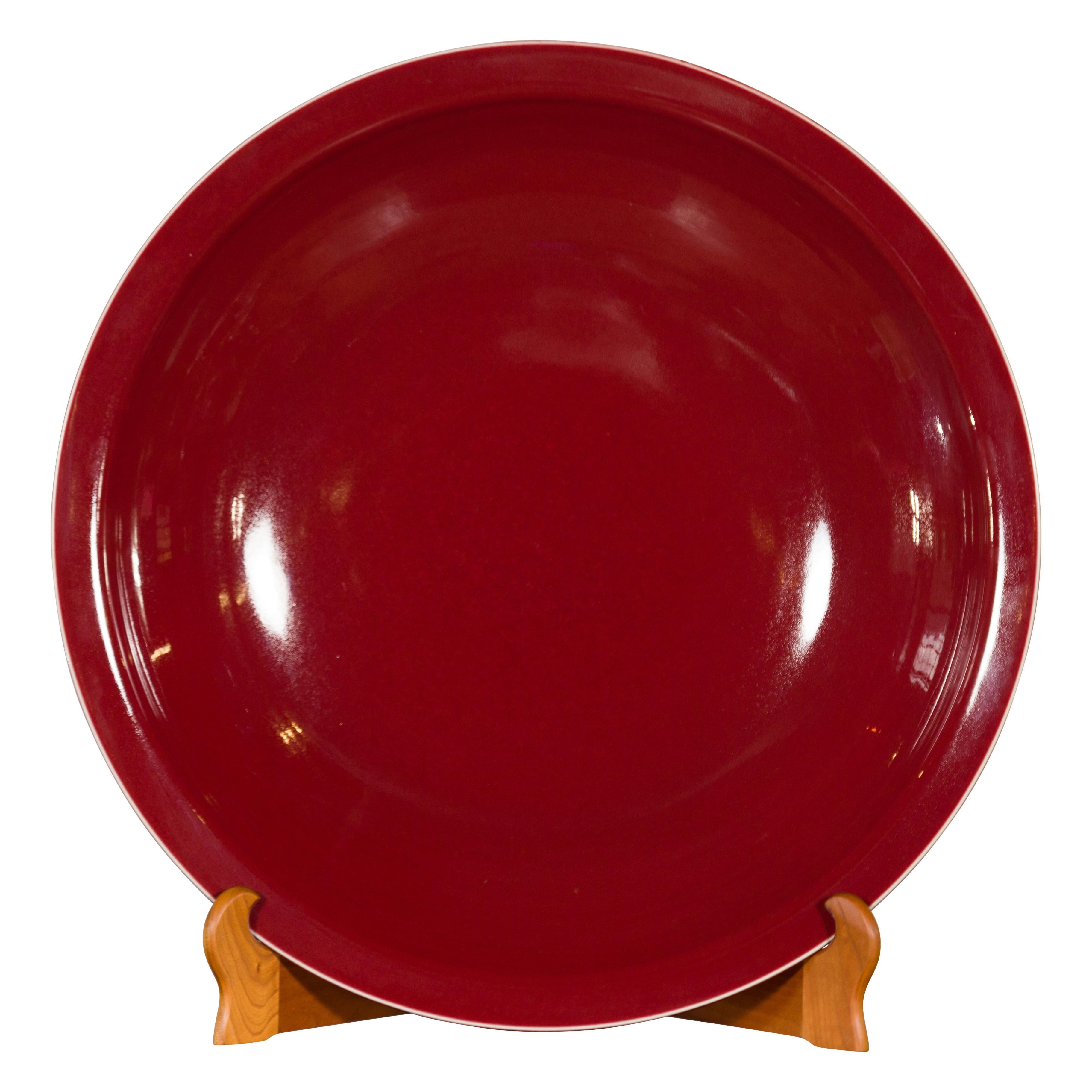 A large Chinese vintage porcelain platter from the mid-20th century, with oxblood color. Created in China during the mid-century period, this porcelain platter captures our attention with its elegant lines and deep oxblood color. Accented with a