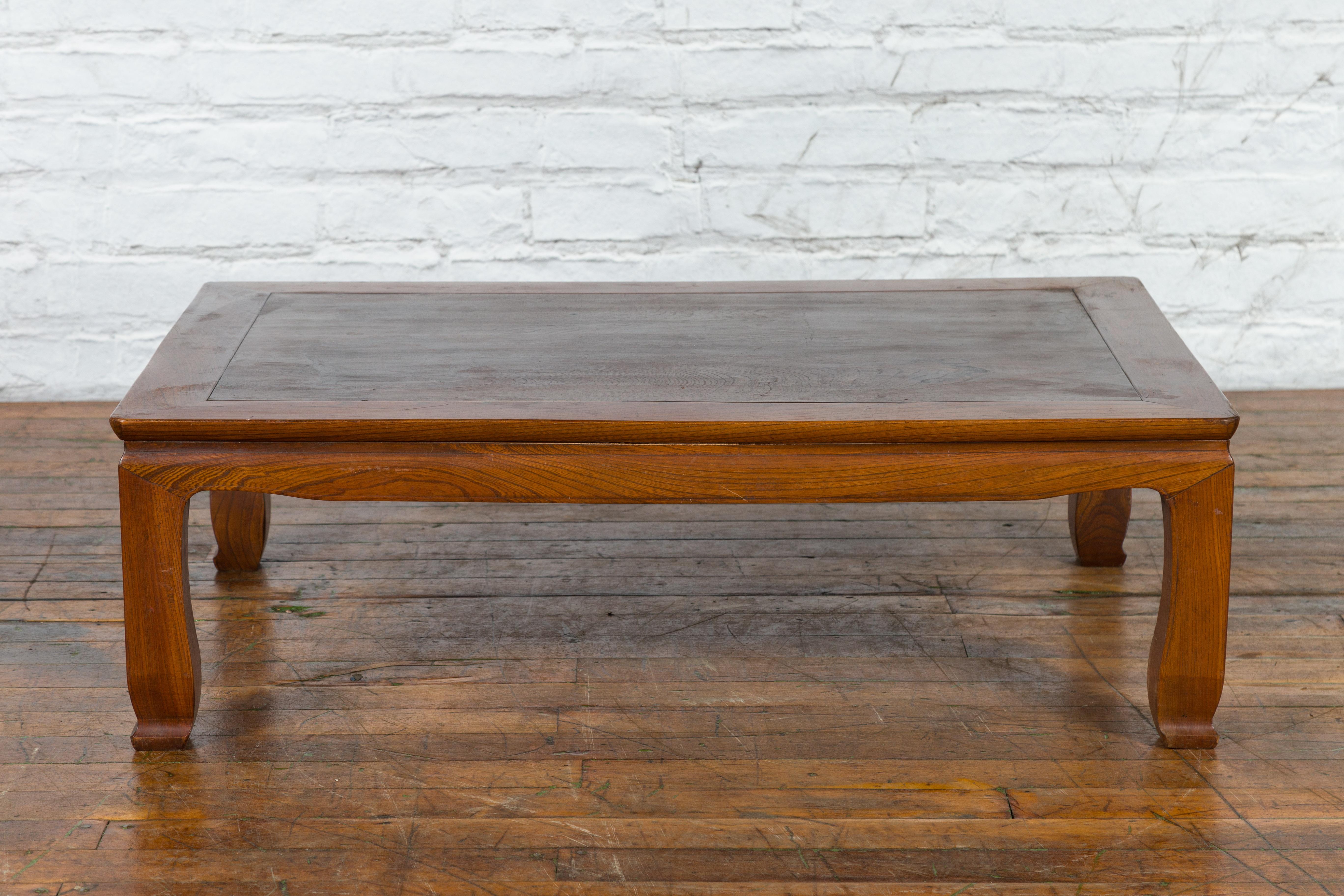 A Chinese vintage low coffee table from the late 20th century, with two-toned top, scalloped apron and scrolling feet. Created in China during the second half of the 20th century, this vintage coffee table features a rectangular top with darker
