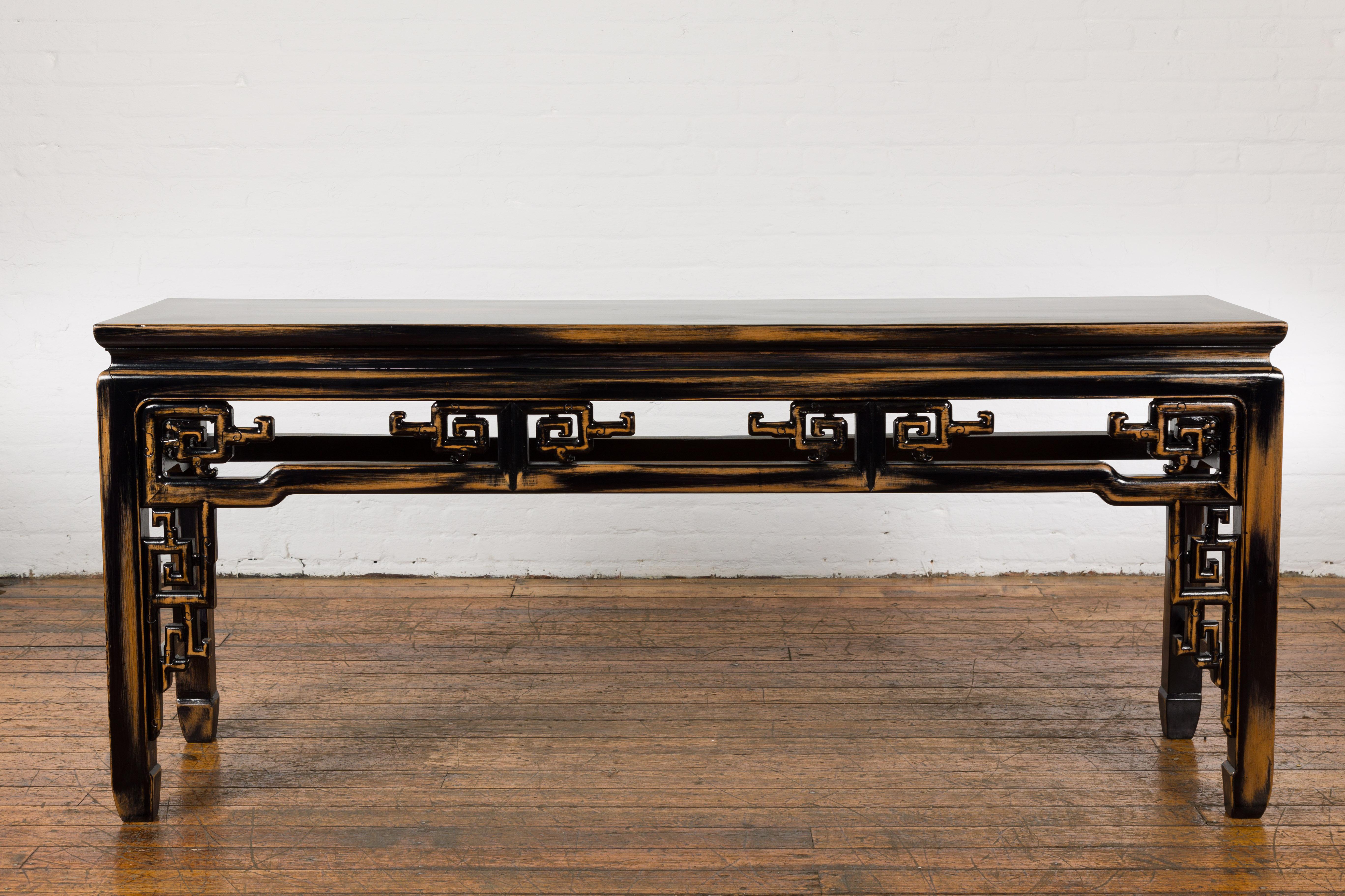 A Chinese Vintage Black and Brown Low Console Table from the mid 20th century with carved apron. Embrace the allure of vintage splendor with this stunning mid-20th century Chinese low console table, which skillfully blends distressed black and brown