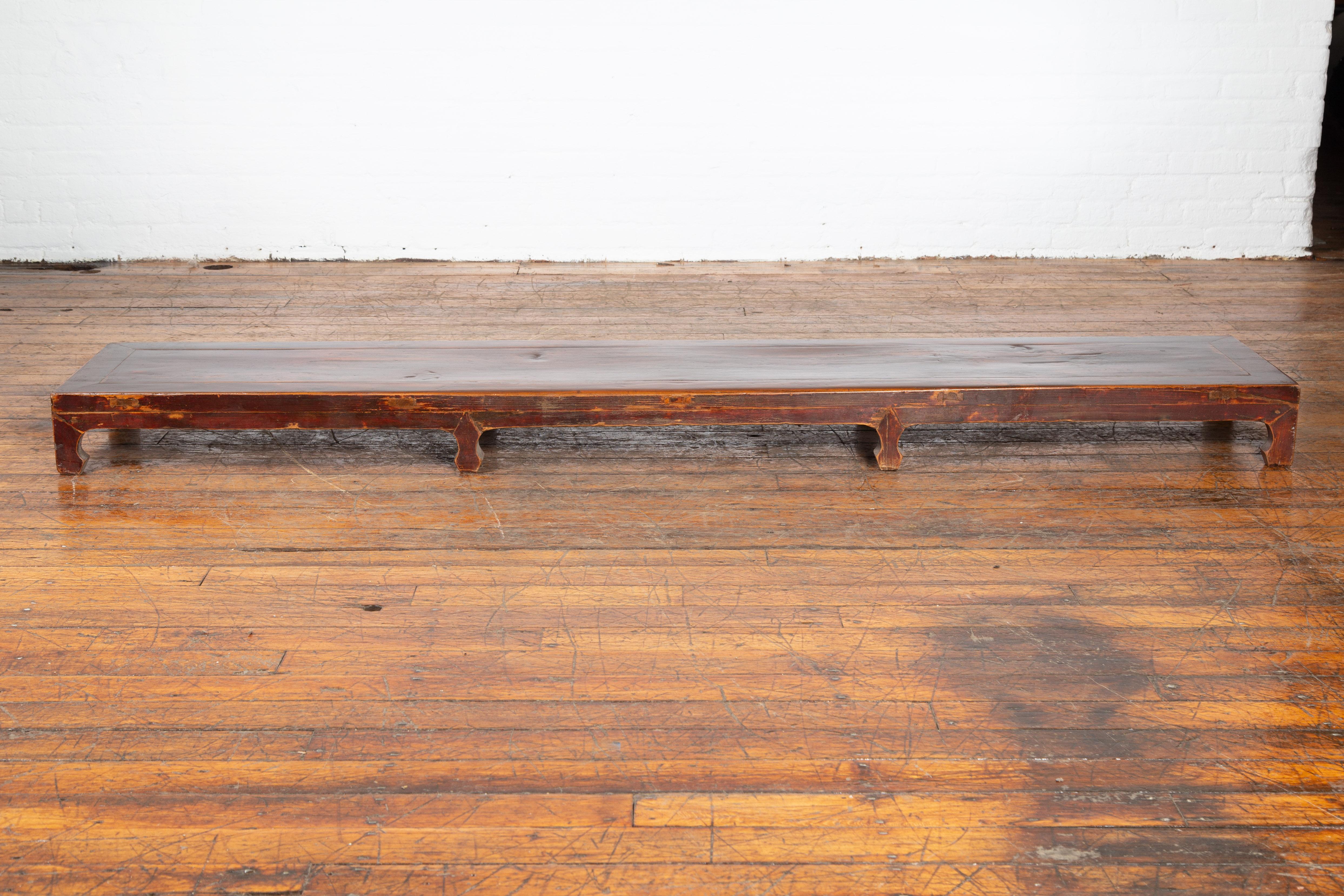 Une table basse Kang vintage chinoise du milieu du 20ème siècle, avec une laque multicolore. Créée en Chine au milieu du siècle dernier, cette table basse Kang présente un plateau rectangulaire long et étroit, surmonté de huit petits pieds sculptés.