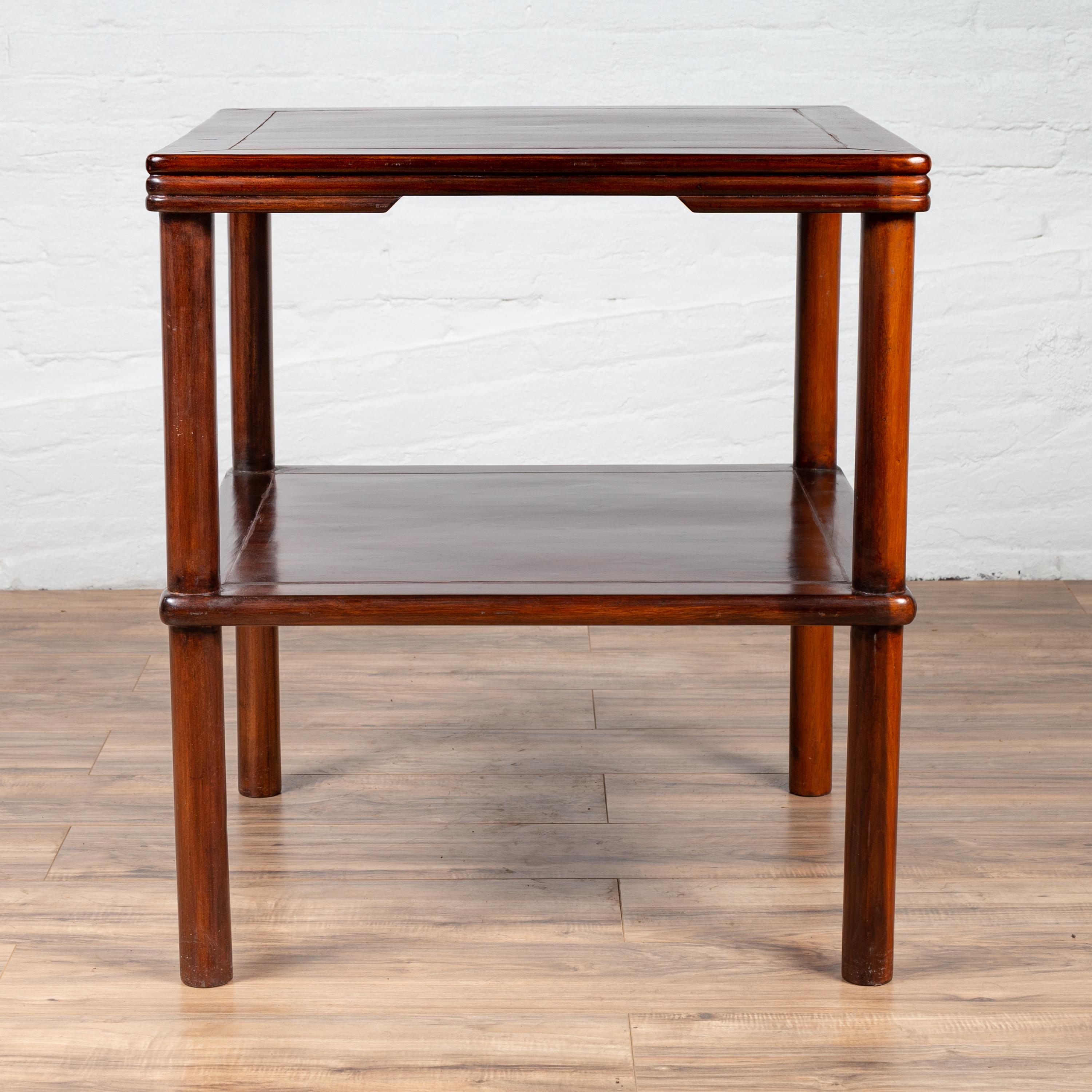 A vintage Chinese square-shaped side table from the mid-20th century, with molded accents, lower shelf and cylindrical legs. Born in China during the midcentury period, this charming side table features a square top with central board and molded