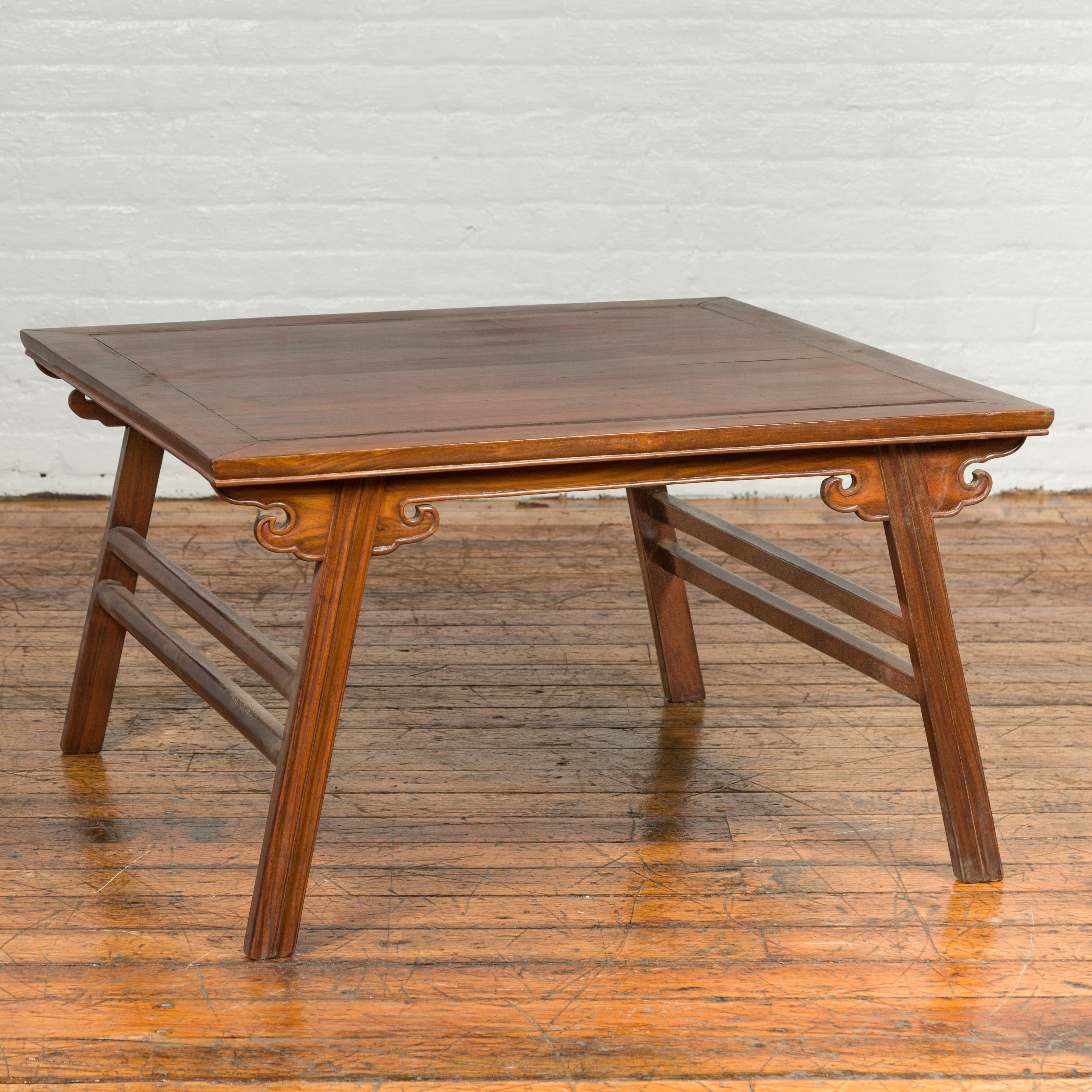 A vintage Chinese Ming Dynasty style elmwood coffee table from the mid-20th century, with carved spandrels and splaying legs. Born in China during the midcentury period, this vintage Ming style elm coffee table features a rectangular top with