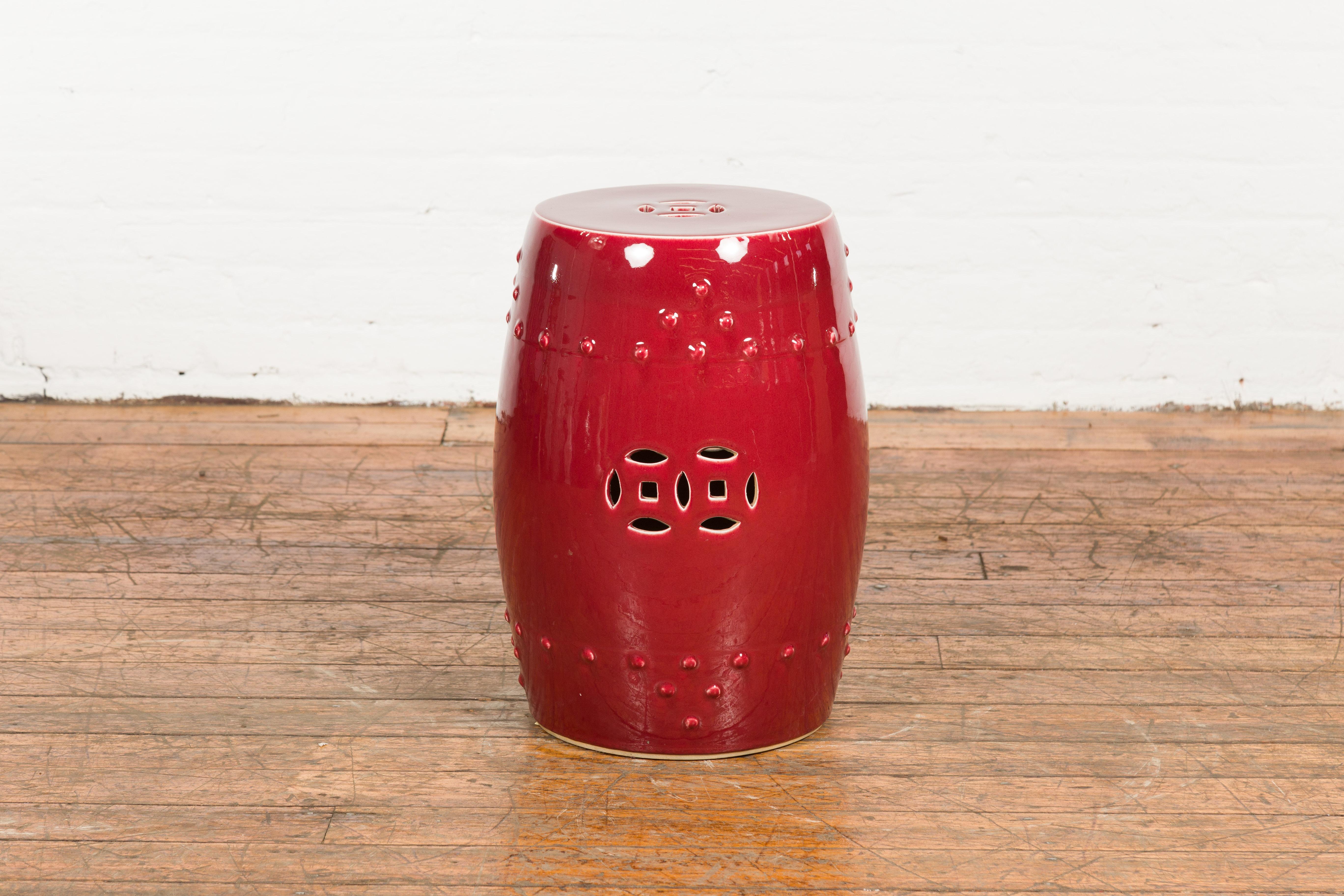A Chinese vintage oxblood glazed ceramic garden stool from the Mid-20th Century, with pierced and raised motifs. Created in China during the midcentury period, this elegant garden stool charms us with its oxblood glazed finish and delicate décor.