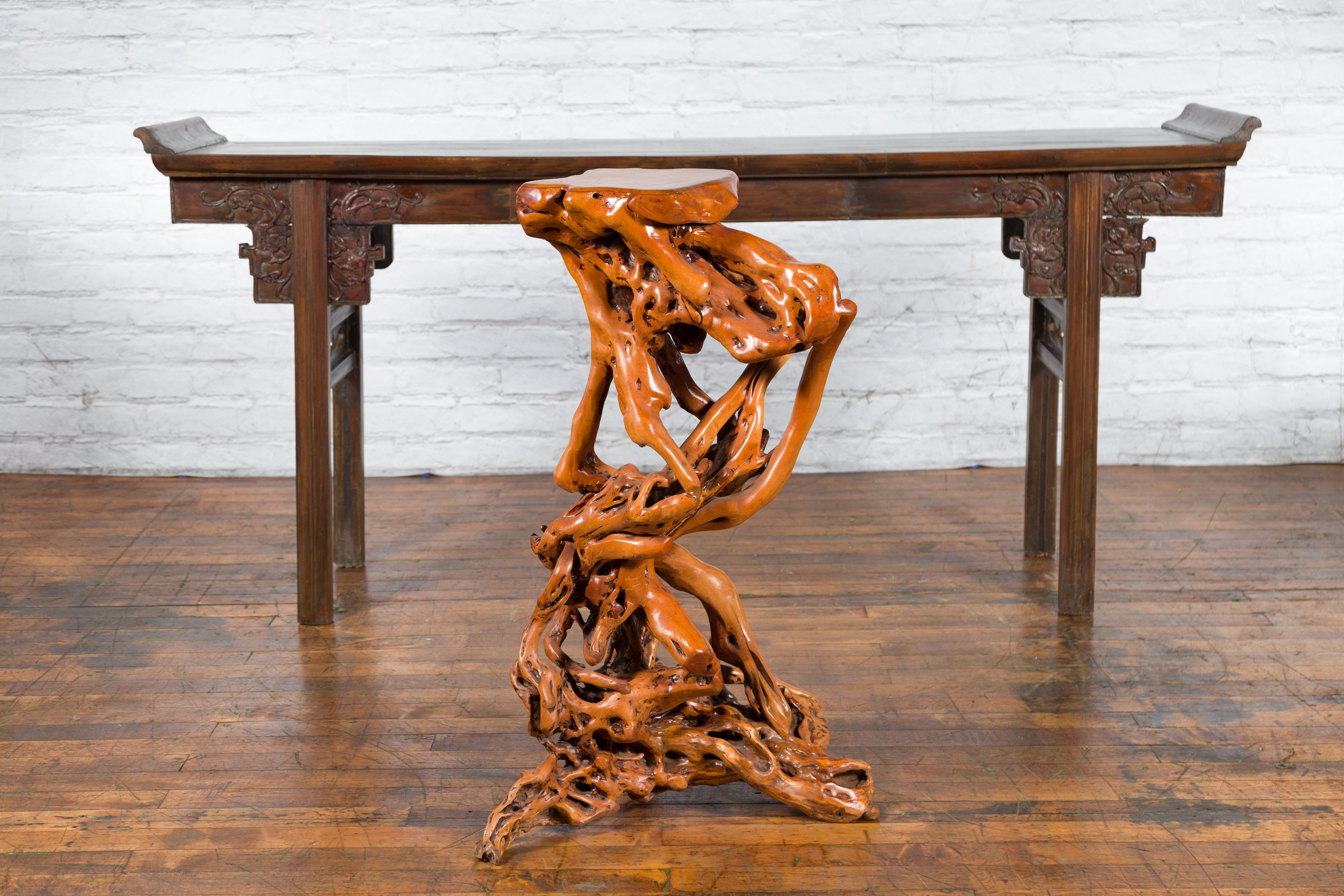 A vintage Chinese sculptural pedestal from the mid 20th century, made from a tree root with lacquered finish. Created in China during the Midcentury period, this pedestal attracts our immediate attention with its intricate lines and warm color. Made