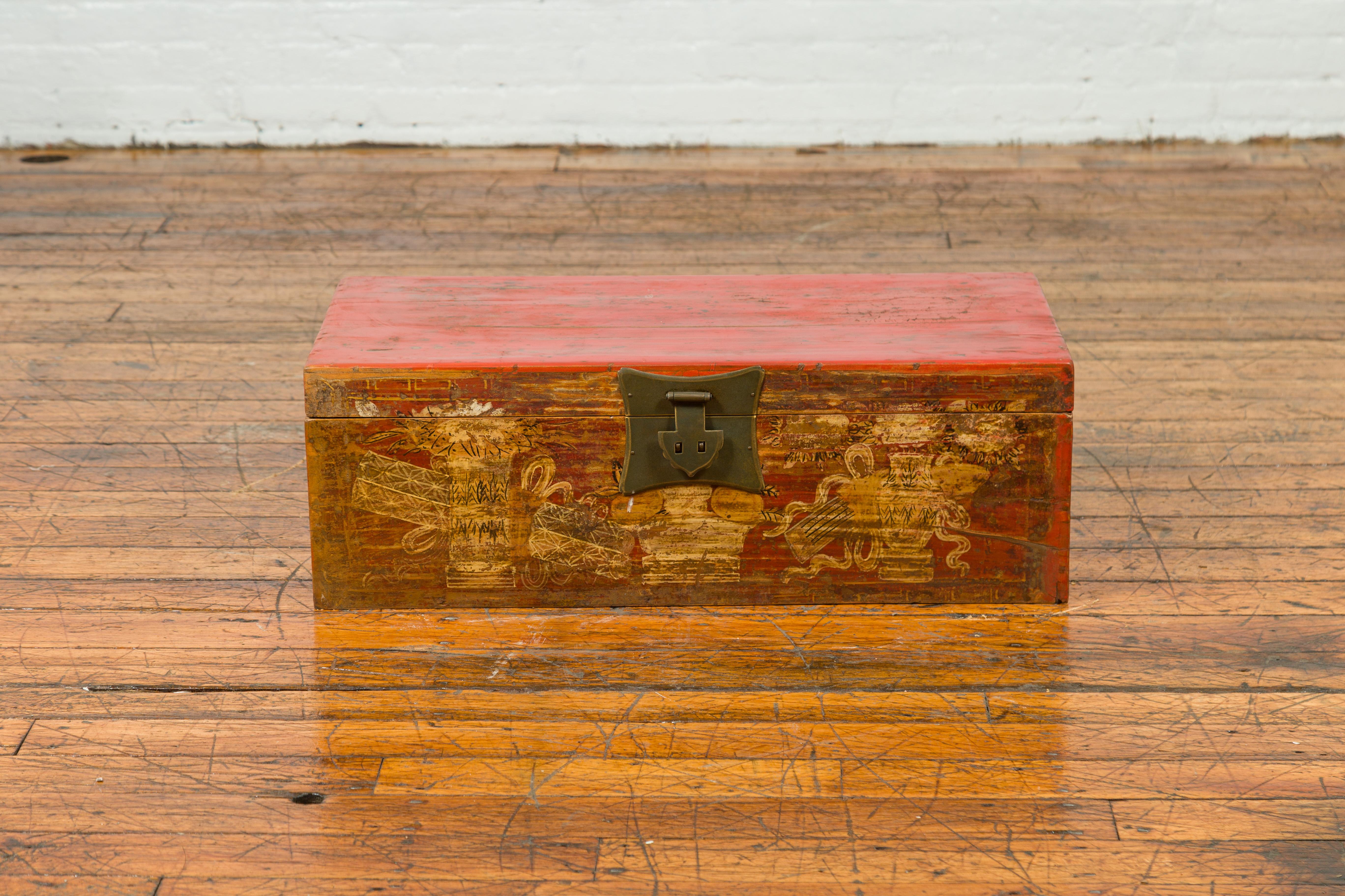 A Chinese vintage red lacquered box from the mid-20th century with golden motifs. Created in China during the midcentury period, this decorative box features a red lacquered ground adorned with golden vases and scrolls in the front. The lid opens