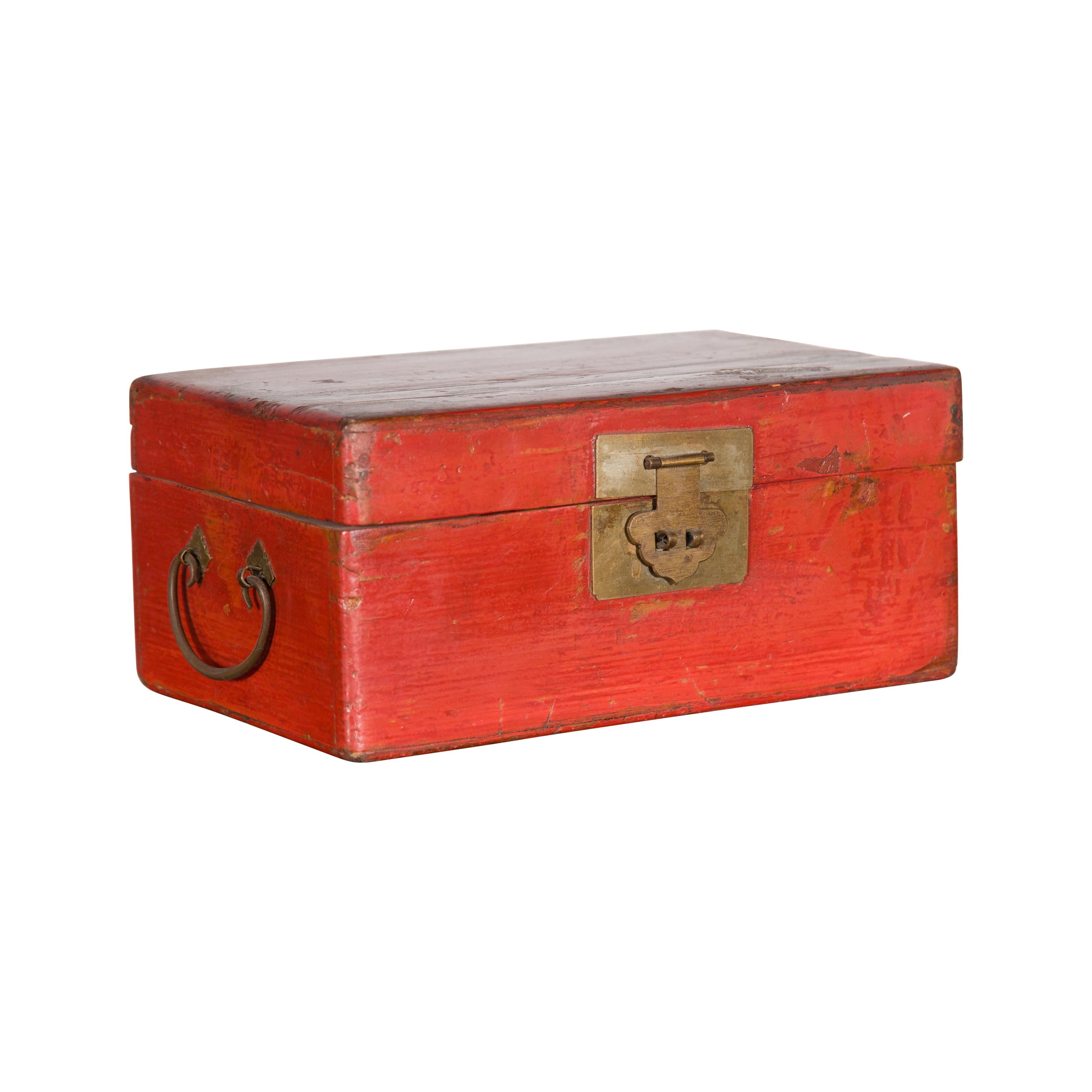 A vintage Chinese red lacquered document box from the mid 20th century, with brass hardware. Created in China during the midcentury period, this document box features a red lacquered lid opening thanks to a traditional lock to reveal a small