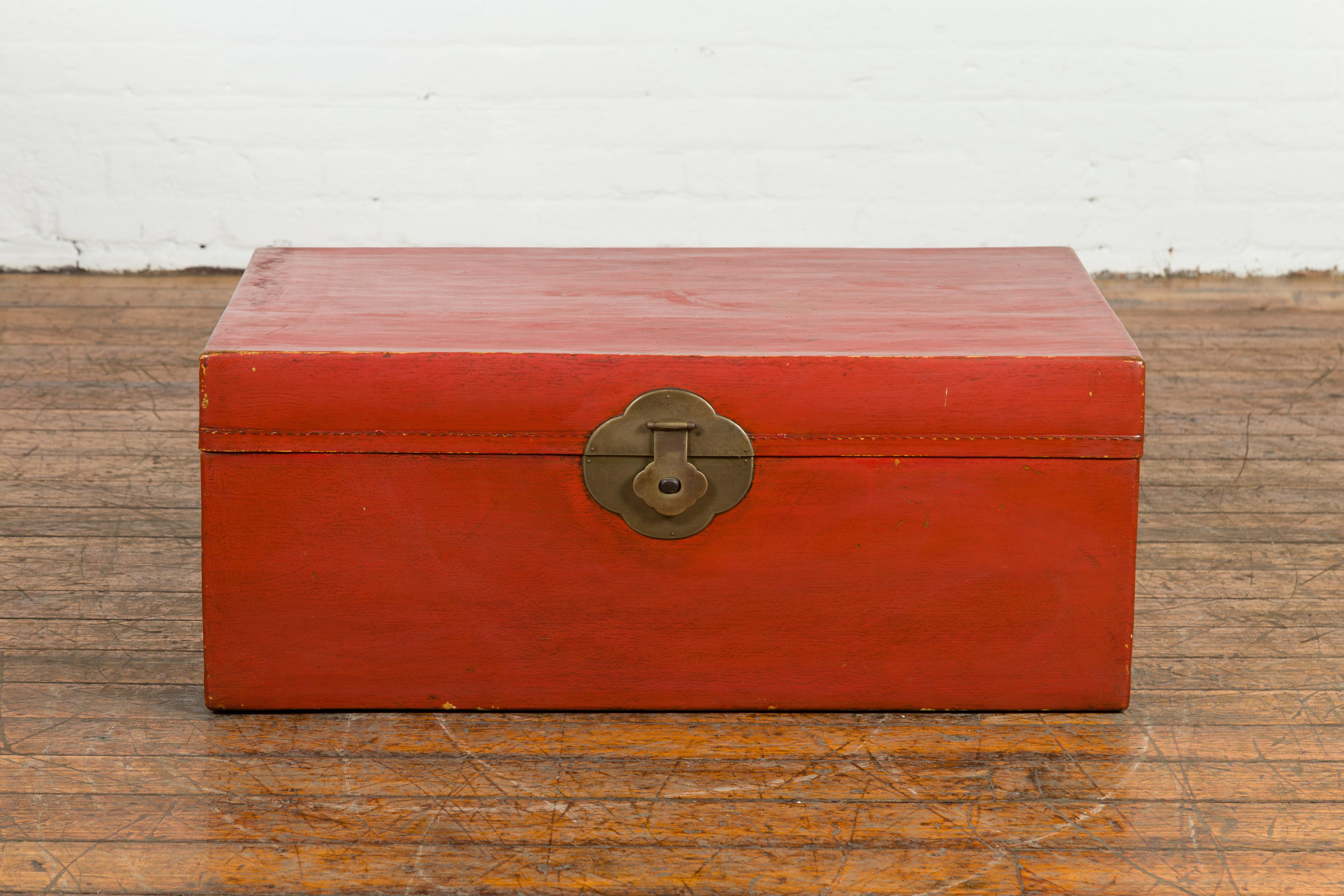 A vintage Chinese blanket chest from the Mid-20th Century with red lacquered leather, brass hardware and blue fabric lining on the inside. Created in China during the midcentury period, this red lacquered leather trunk features a rectangular lid