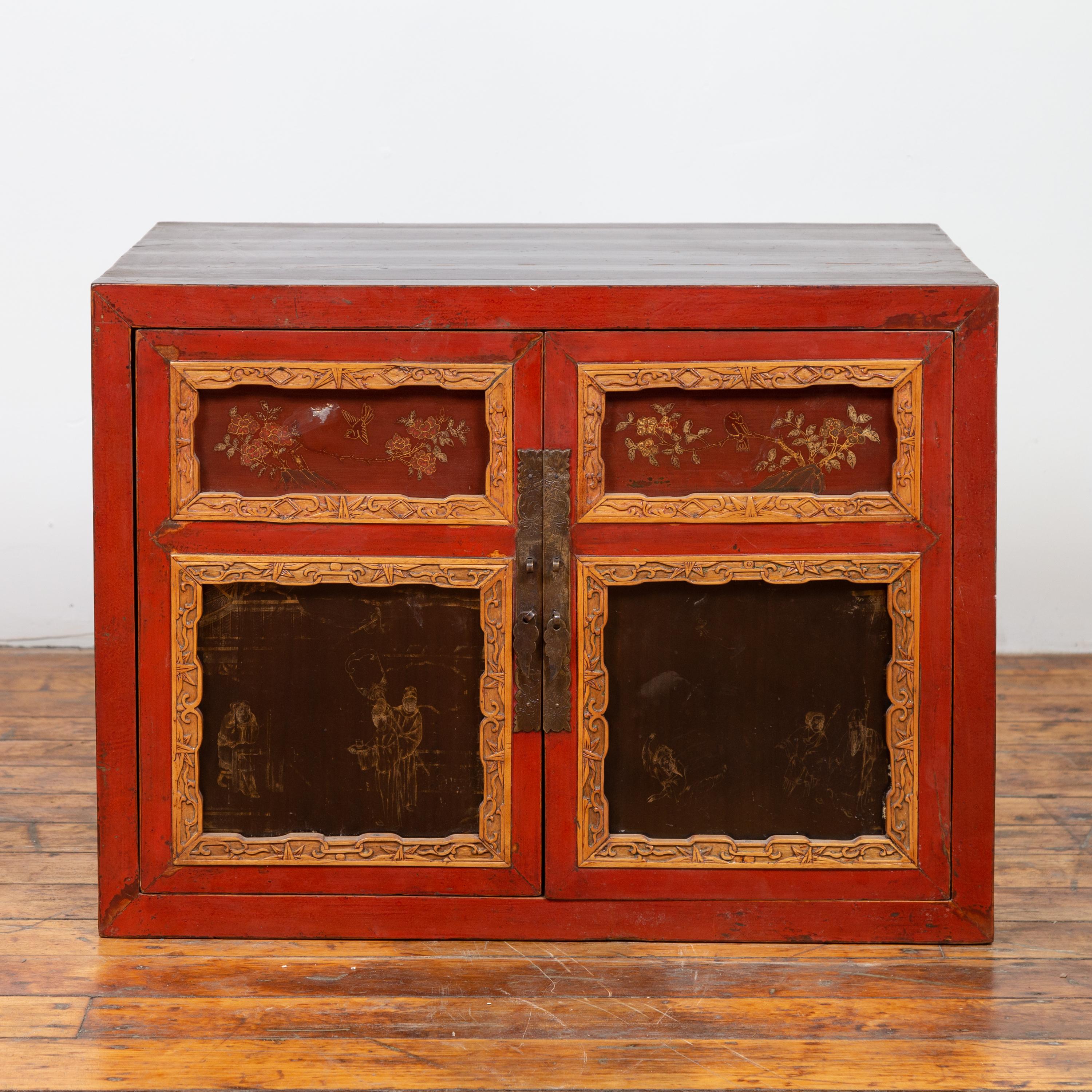 A Chinese small vintage red lacquered cabinet from the early 20th century, with golden tones and hand painted details. Born in China during the midcentury period, this small cabinet charms us with its red lacquered finish, accented with carved and