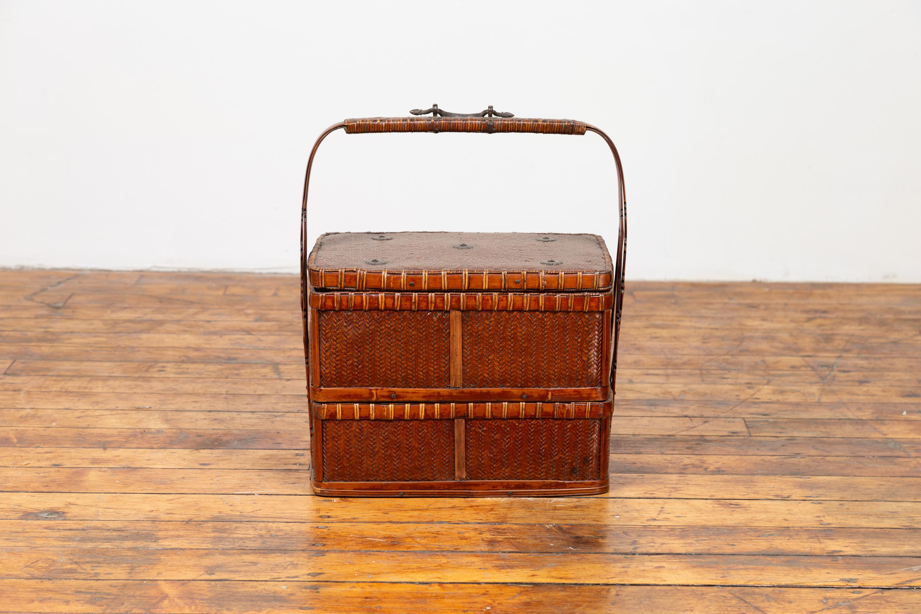 A Chinese vintage small tiered rattan and bamboo picnic basket from the mid-20th century, with large handle. Born in China during the midcentury period, this charming picnic basket features two independent sections, topped with a rectangular lid.