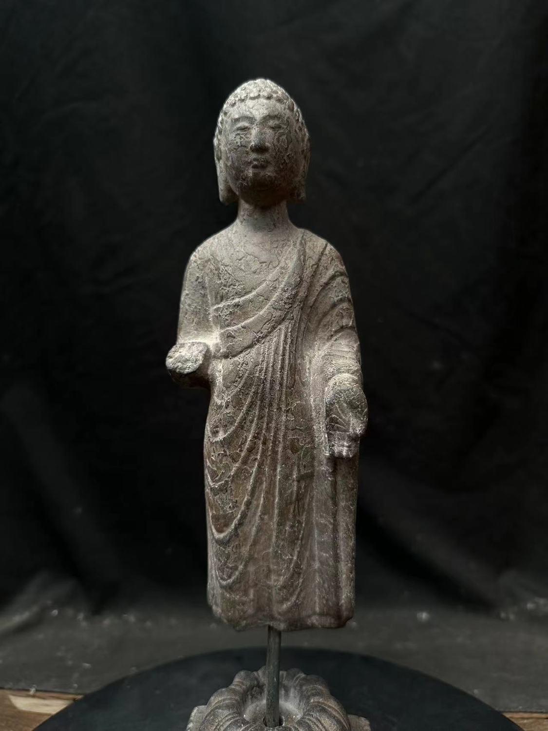 Cette statue chinoise de Bouddha debout, sculptée dans la pierre, est une pièce remarquable de l'artisanat traditionnel, sculptée dans la pierre solide avec des détails fins reflétant l'art bouddhiste. Malgré la perte d'une main, la statue conserve
