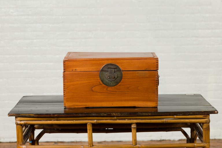 A Chinese vintage treasure box from the mid-20th century with traditional bronze hardware. Born in China during the midcentury period, this wooden treasure box features a linear appearance perfectly contrasted by the presence of traditional bronze