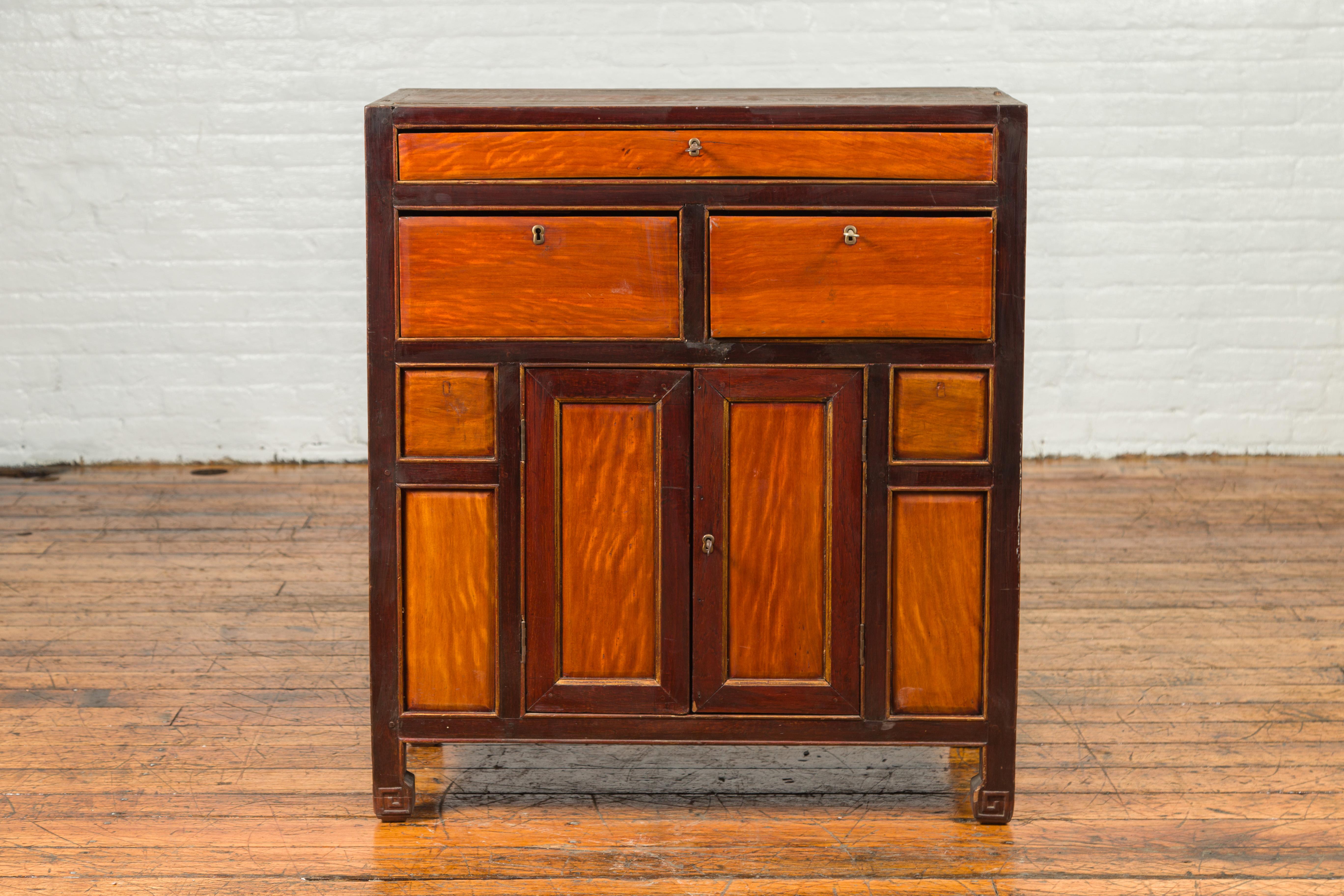 A Chinese vintage two-toned side chest from the mid-20th century, with three drawers over a pair of double doors. Crafted in China during the mid-century period, this side chest attracts our attention with its two-toned finish complimenting the