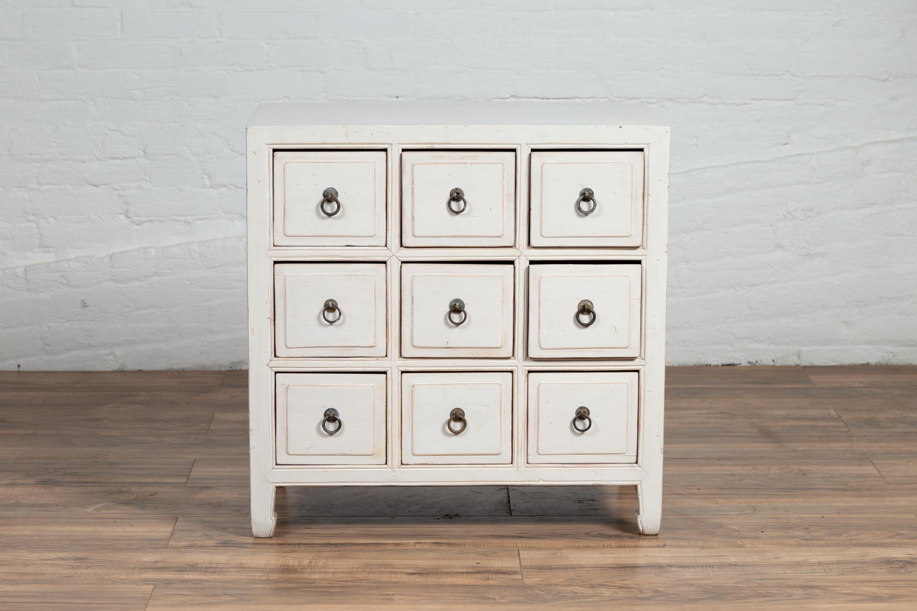 A Chinese vintage white painted wood nine-drawer apothecary chest from the mid-20th century. Born in China during the midcentury period, this lovely apothecary chest features a rectangular top, sitting above a perfectly organized façade, made of