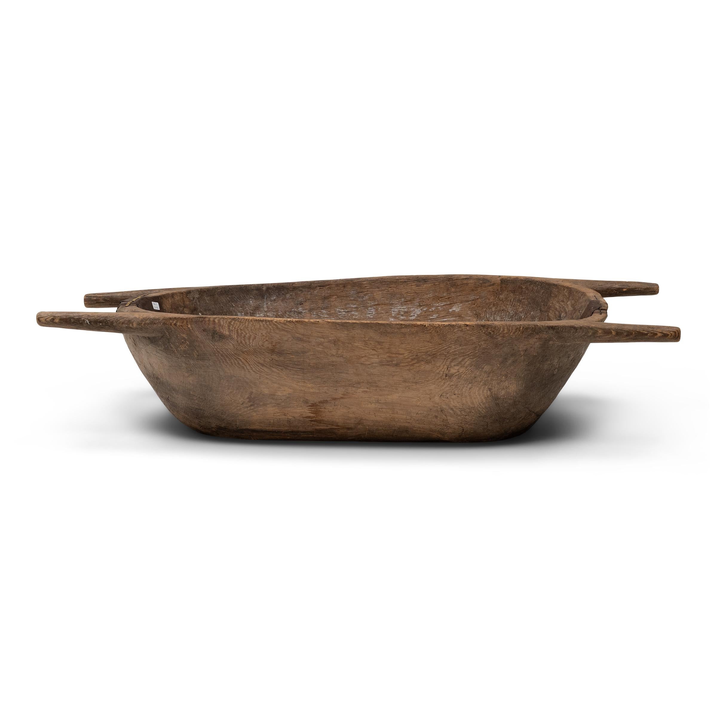 Questo grande vassoio in legno bilancia la struttura rustica con la semplicità minimalista. Ricavato da un solido blocco di legno, il vassoio ha una profonda vasca ovale con lati inclinati e angoli intagliati in maniglie rotonde. Gli anni di