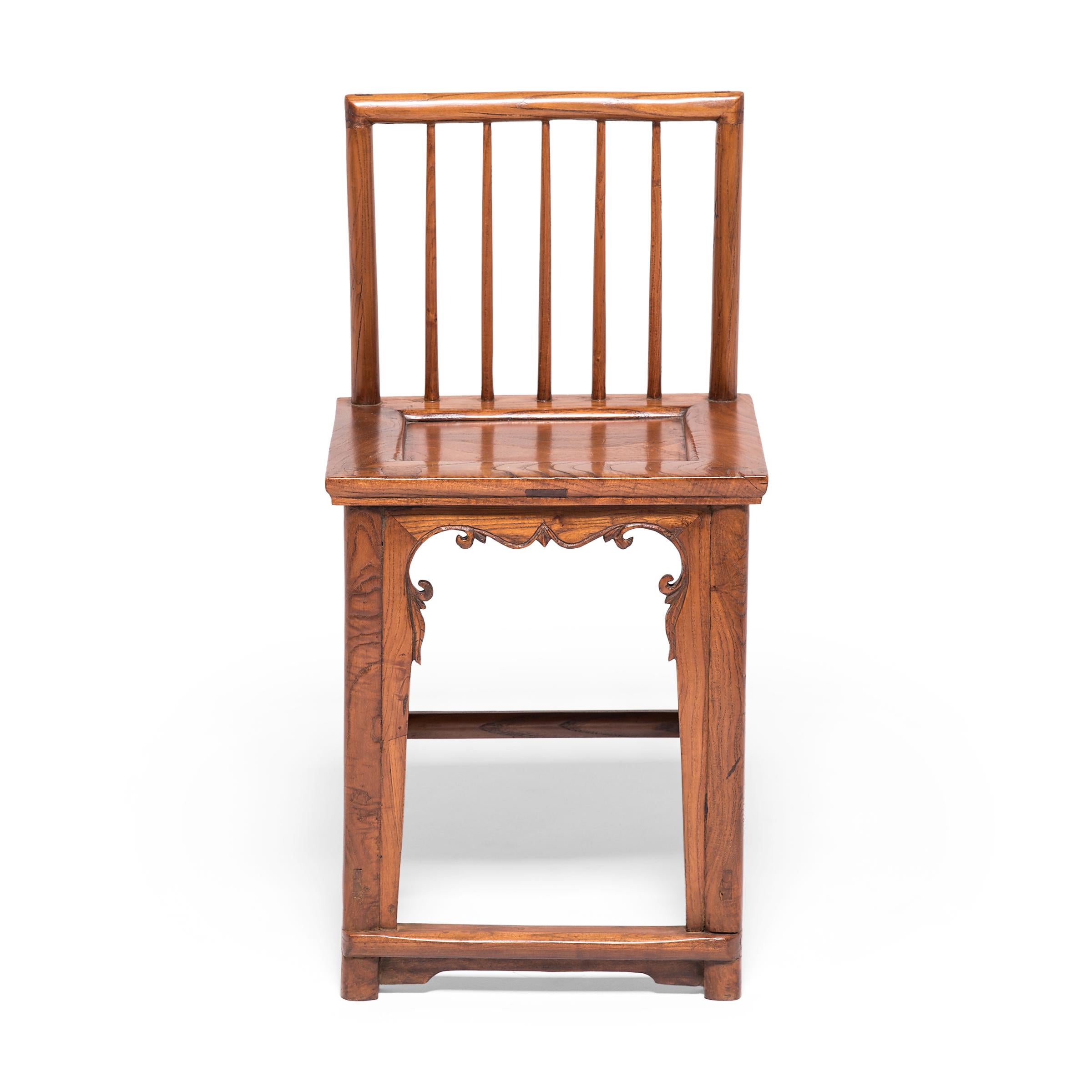 Cette chaise en noyer du début du XXe siècle doit sa grâce aux styles et techniques apparus sous la dynastie Ming, l'âge d'or du mobilier chinois. Les lignes pures de la forme en fuseau sont interrompues par un tablier avant sculpté, orné de fleurs