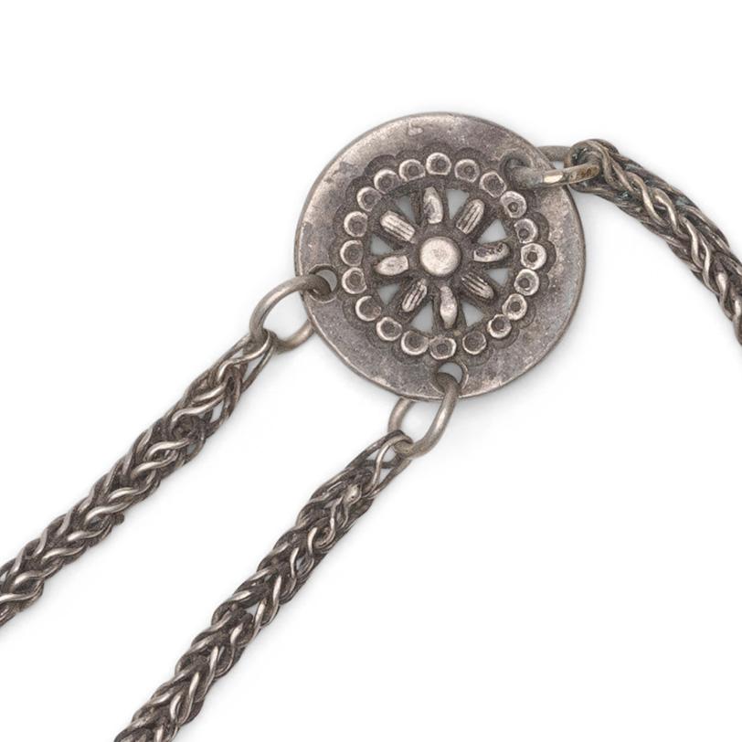 A small Chinese chatelaine tool set strung with a petite white brass spoon and scraper tool. The small tools hang from a charm shaped as the 