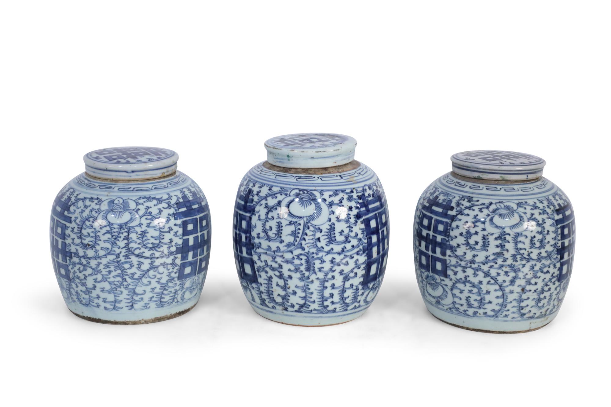 3 antique Chinese (Late 19th Century) similar ceramic ginger jars with blue floral designs surrounding bold, centered characters and geometric patterned bands leading to brown rustic stripes at the mouth openings. Each is topped with a lid depicting