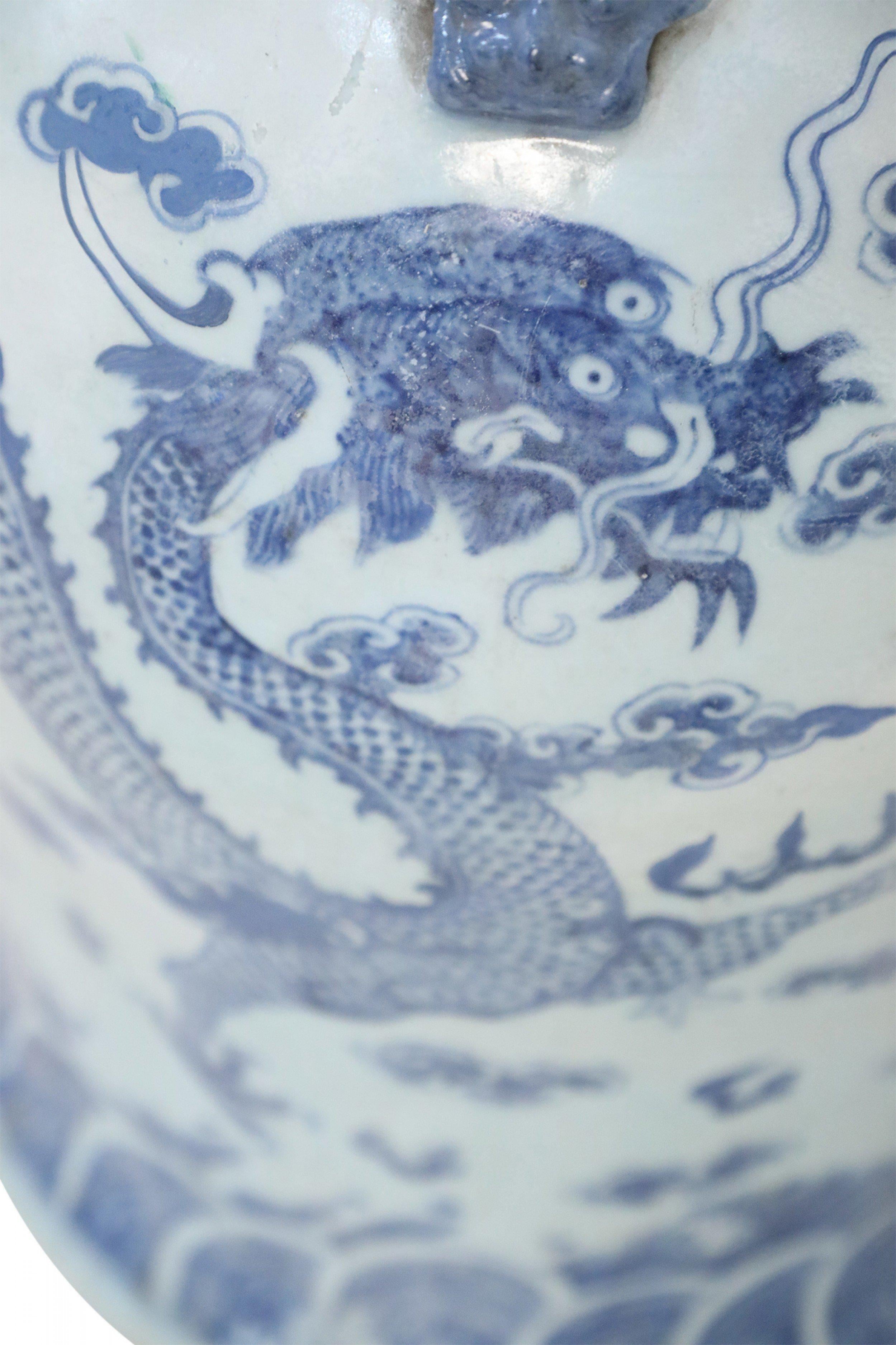 Grande urne chinoise en porcelaine blanche décorée d'un dragon bleu et de motifs de nuages et accentuée par des ornements de dragon autour de l'ouverture.
      