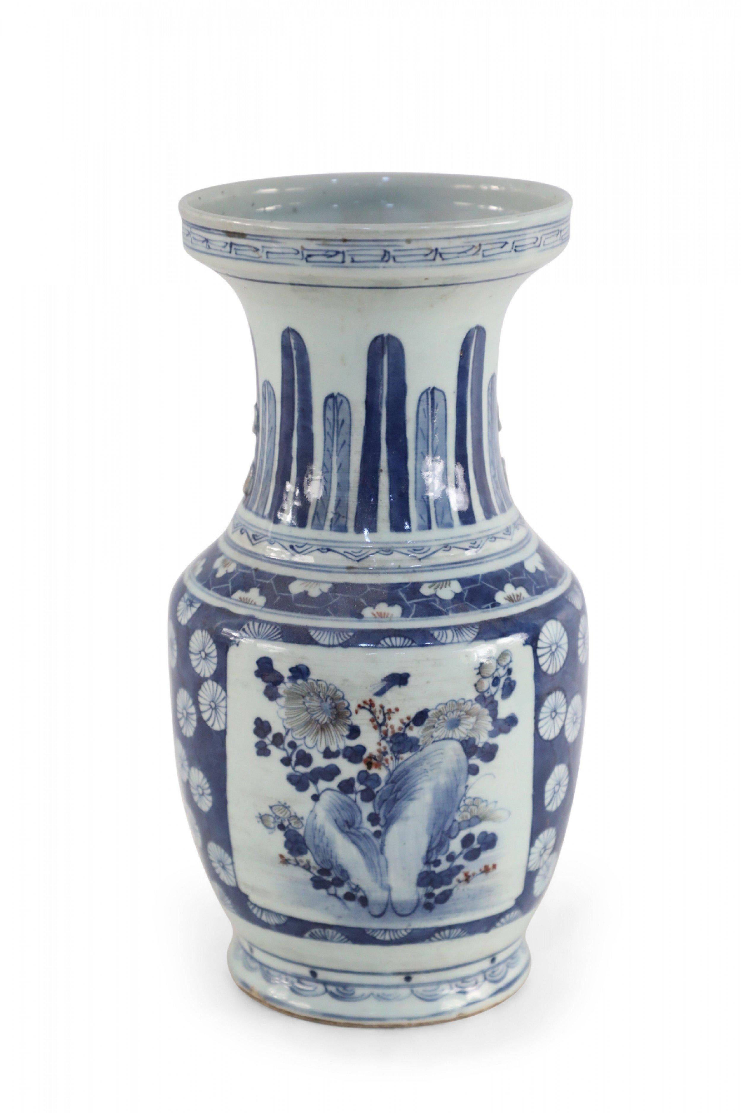 Chinese porcelain urn painted with a blue and white floral background surrounding a center square with a floral arrangement, feathers along the neck in varying shades of blue, and geometric patterned bands at the top, middle and base.
  