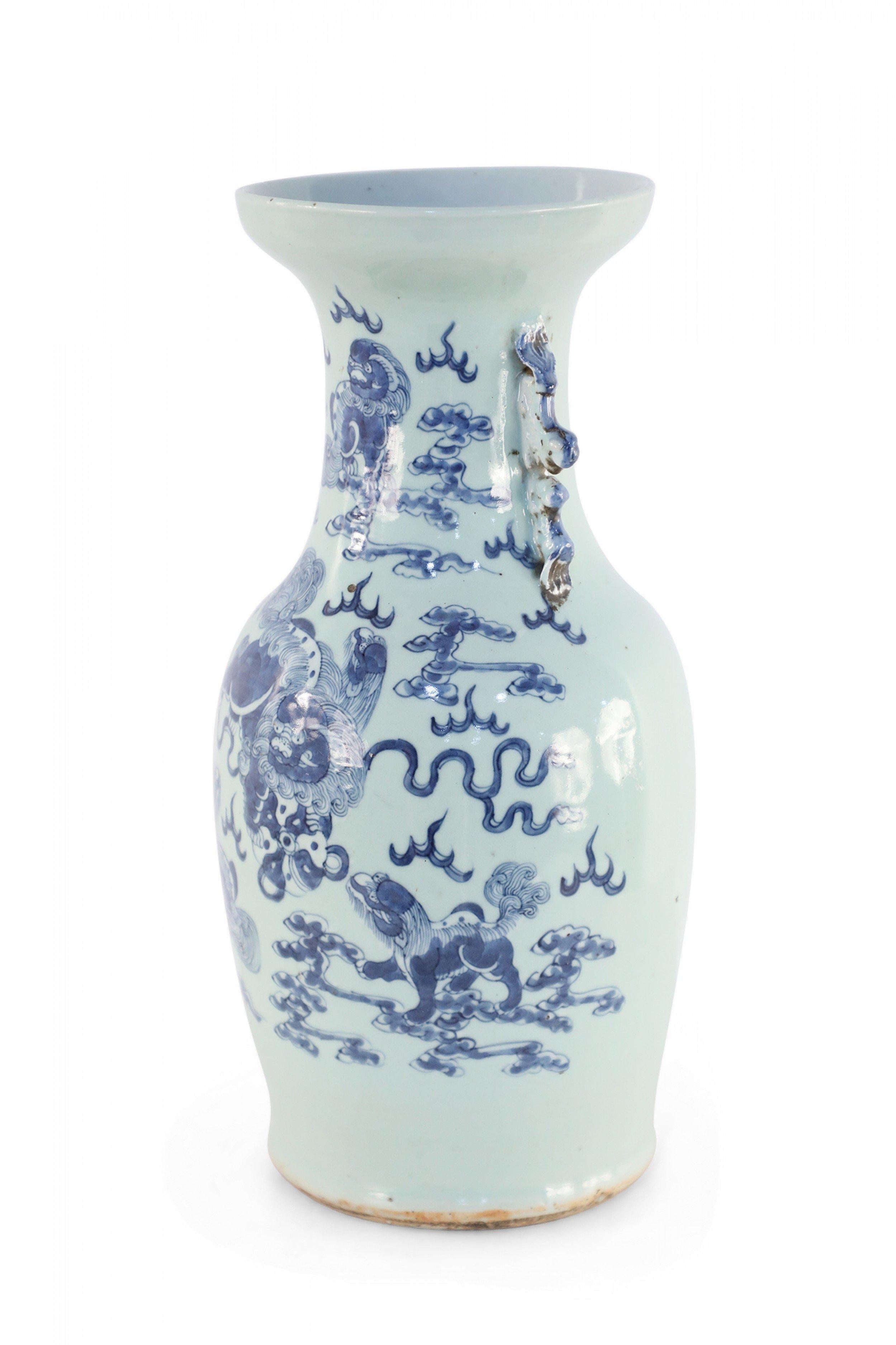 Antique Chinese (Late 19th Century) off-white porcelain urn decorated with blue foo dogs playing amid the clouds and accented in two pale blue scrolled handles along the neck.
  